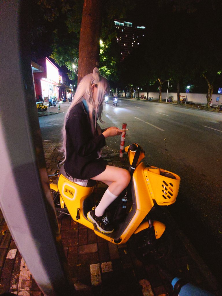 穿着白毛衣的女人坐在黄色的摩托车上。