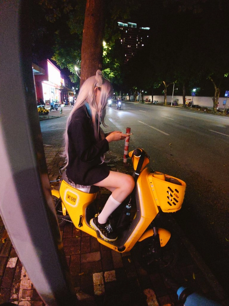 穿着白毛衣的女人坐在黄色的摩托车上。