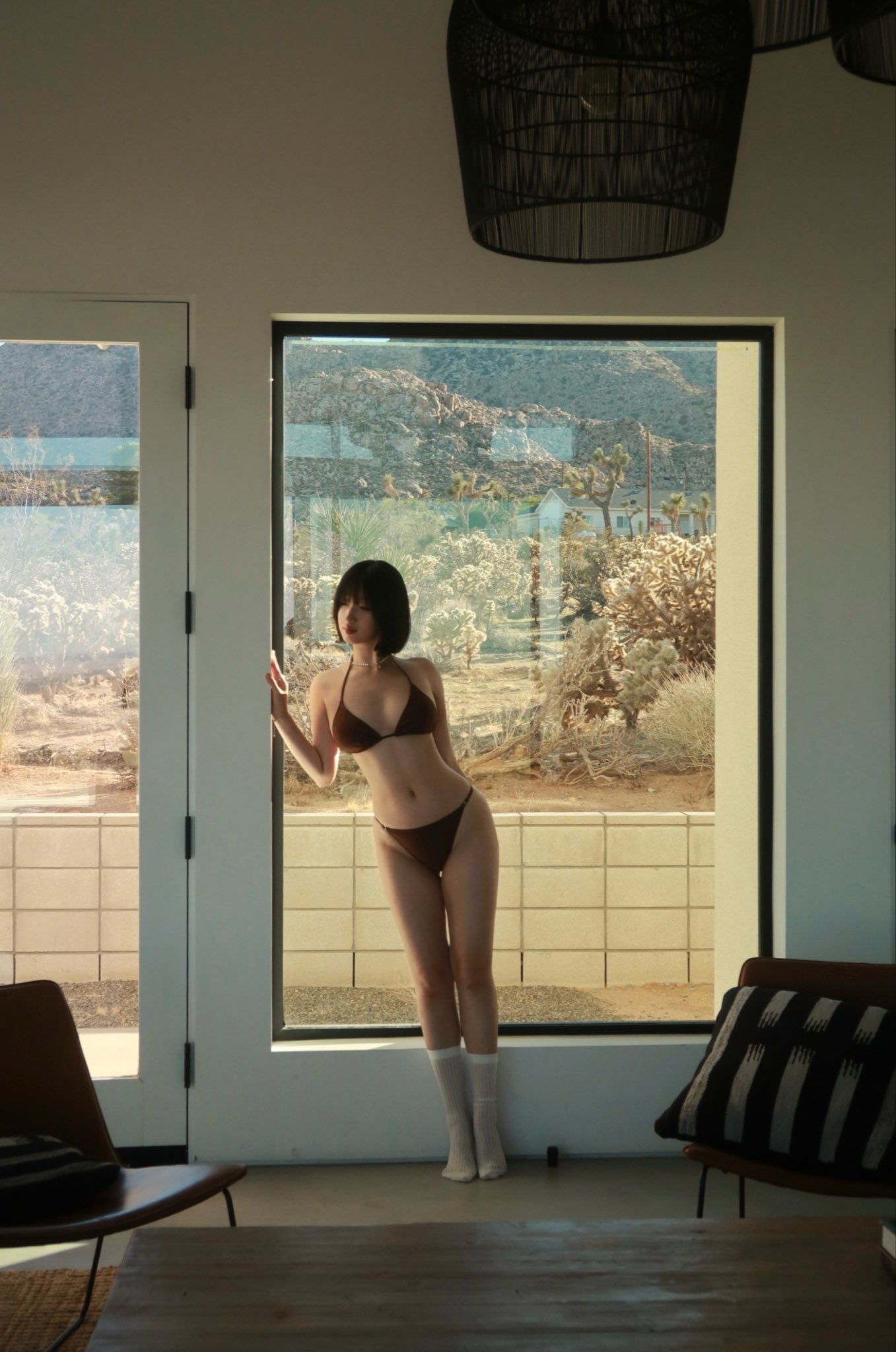 穿比基尼的女人站在窗前。