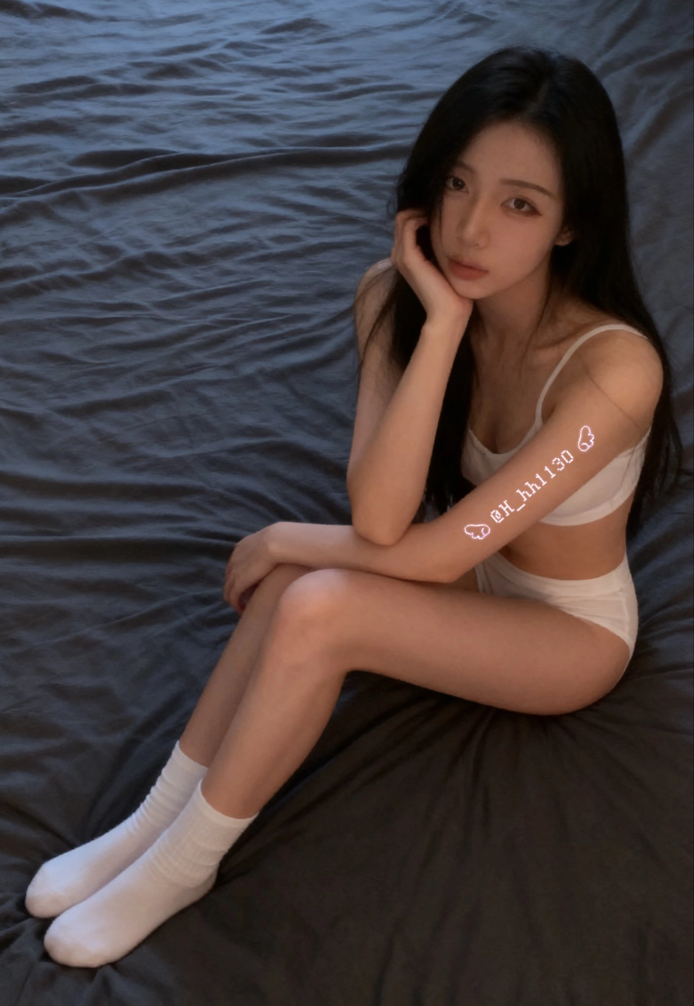 手臂上有纹身的女人坐在床上。