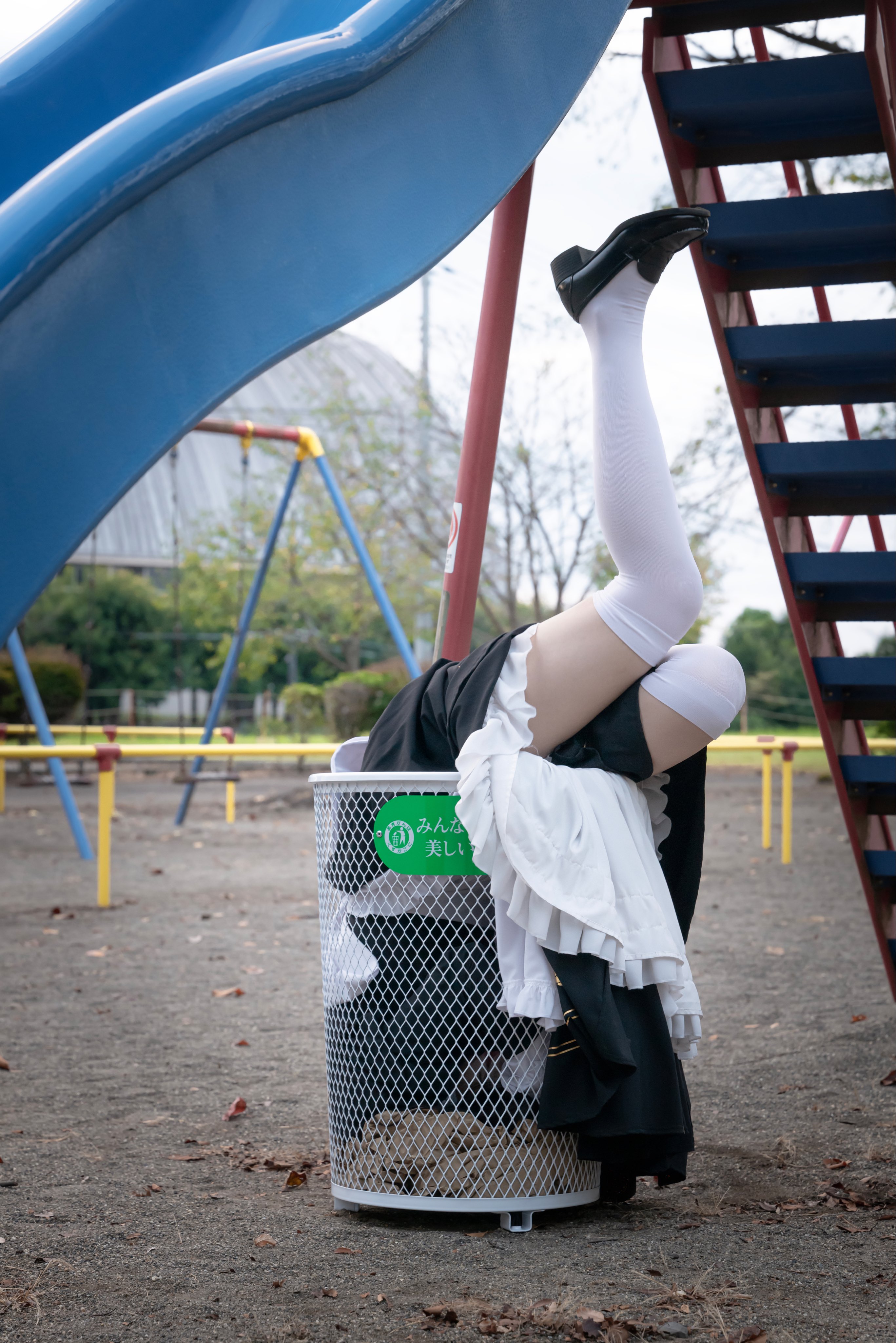 穿着女仆服装的人坐在垃圾桶里。