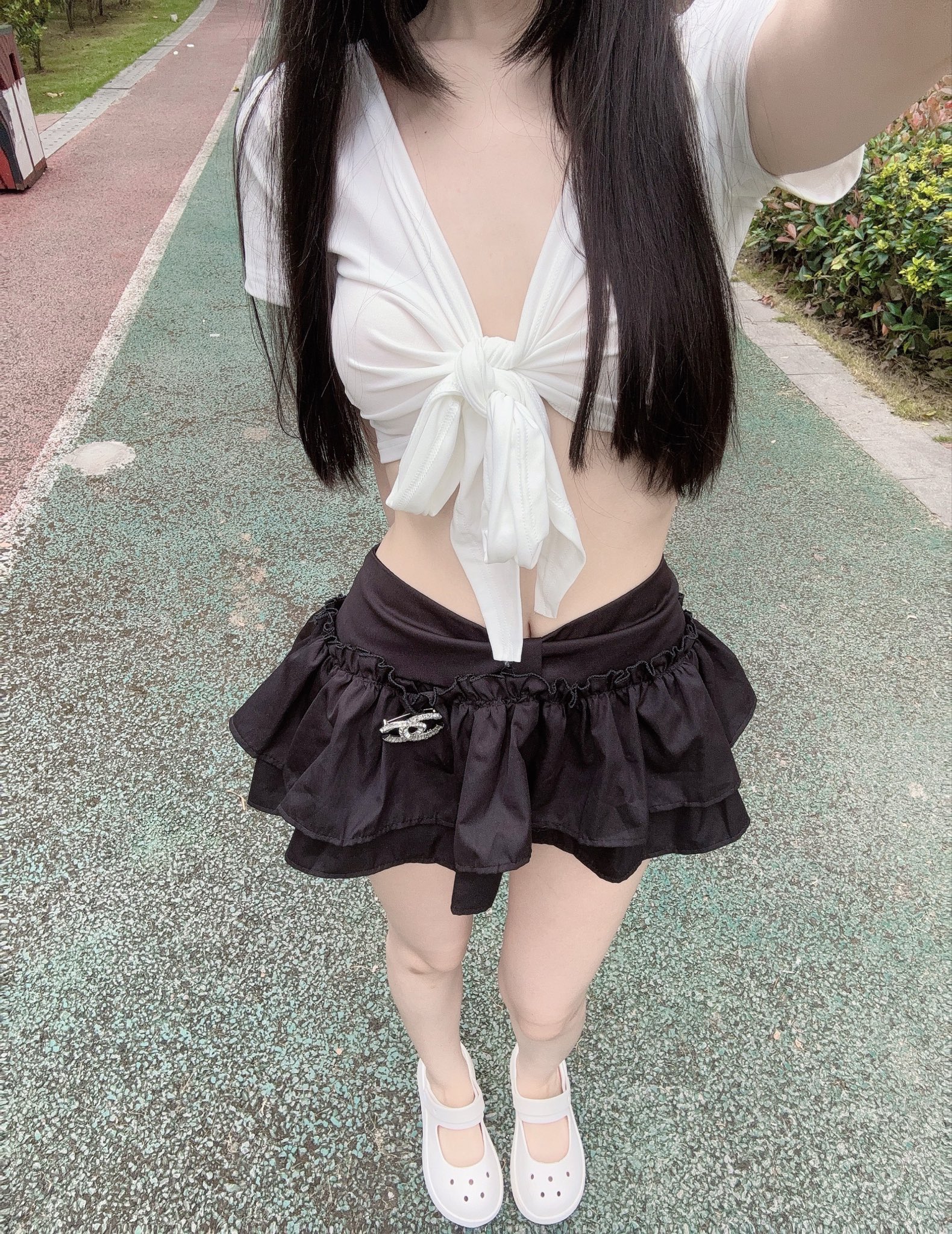 一位女人穿着一件白色衬衫和黑色短裤,戴着一件白色弓链。