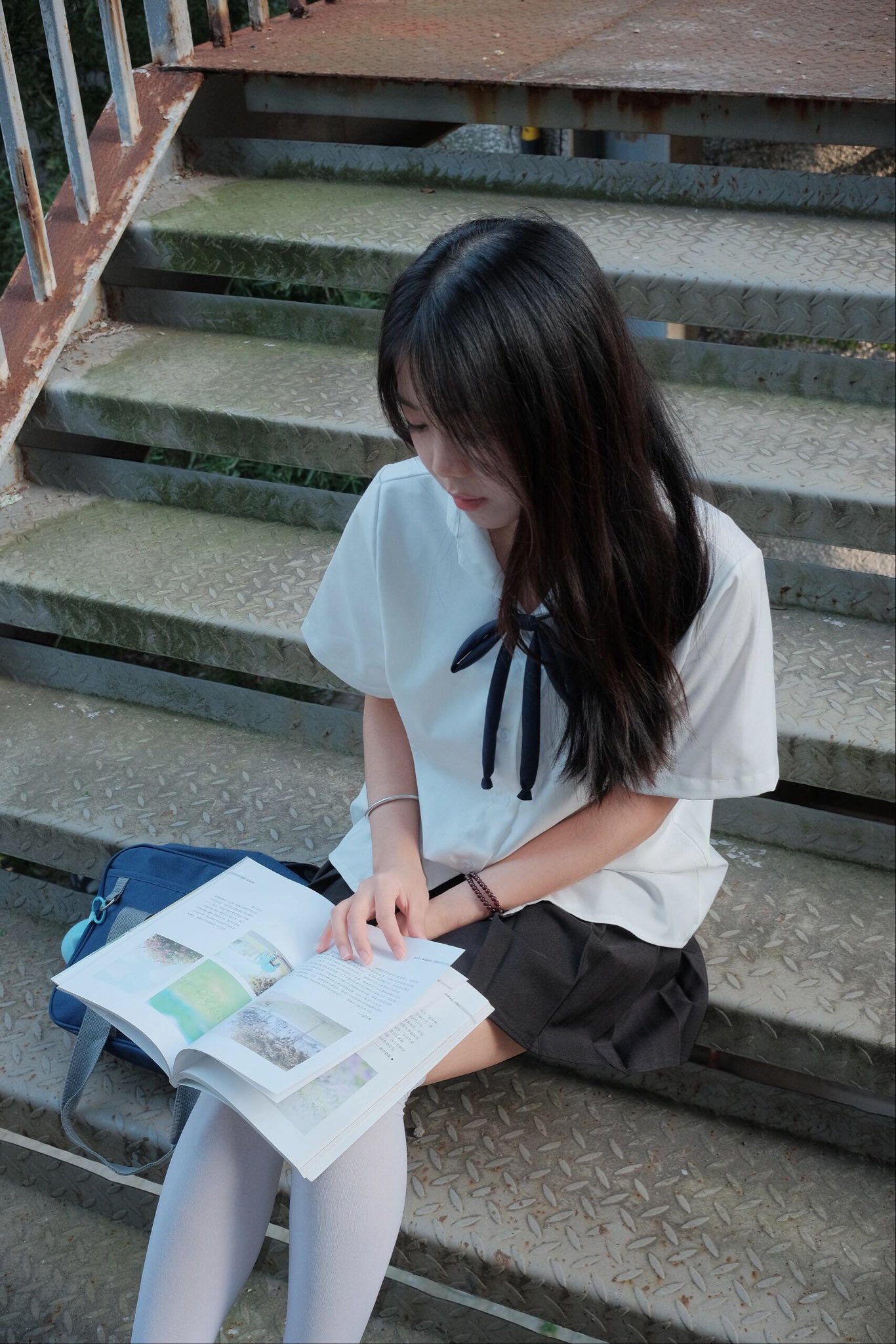 头发上有蓝弓的女孩指着一本书。