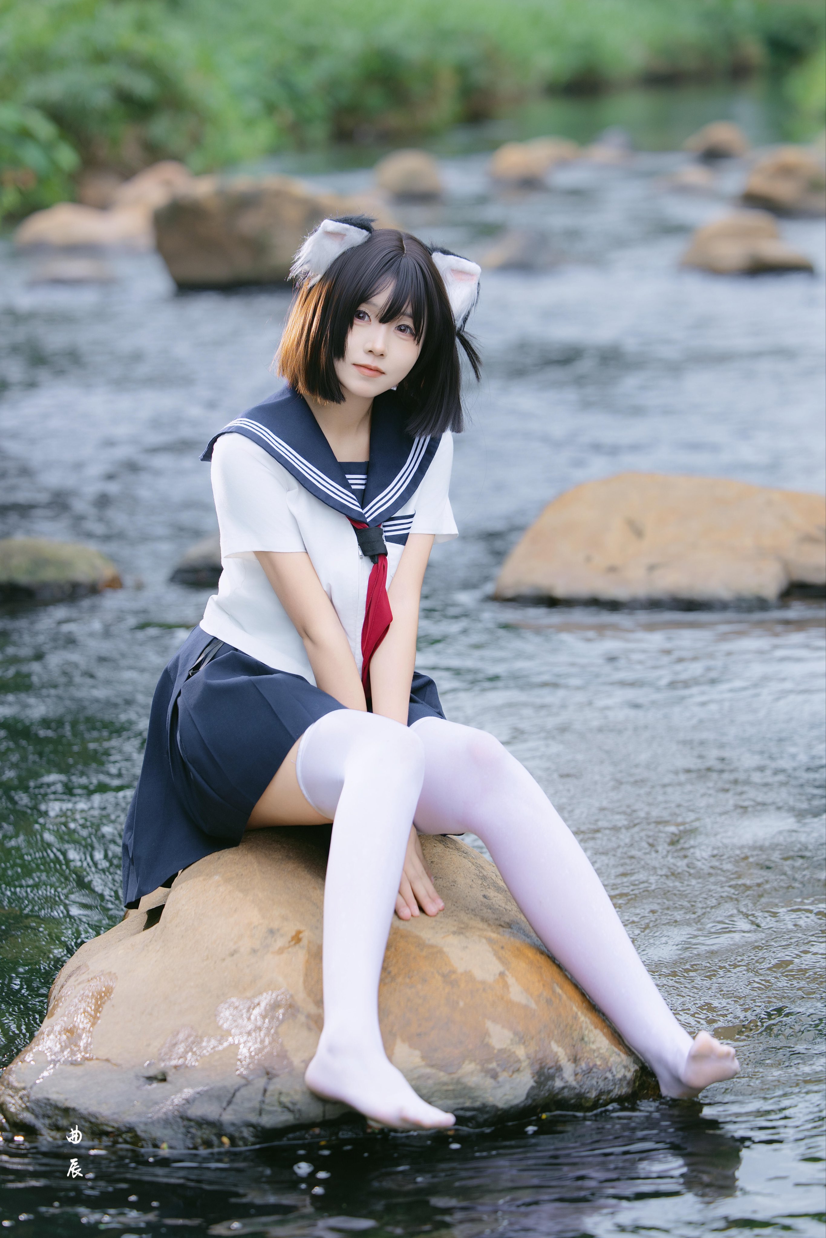 穿着红色衬衫的女孩坐在一块石头上。