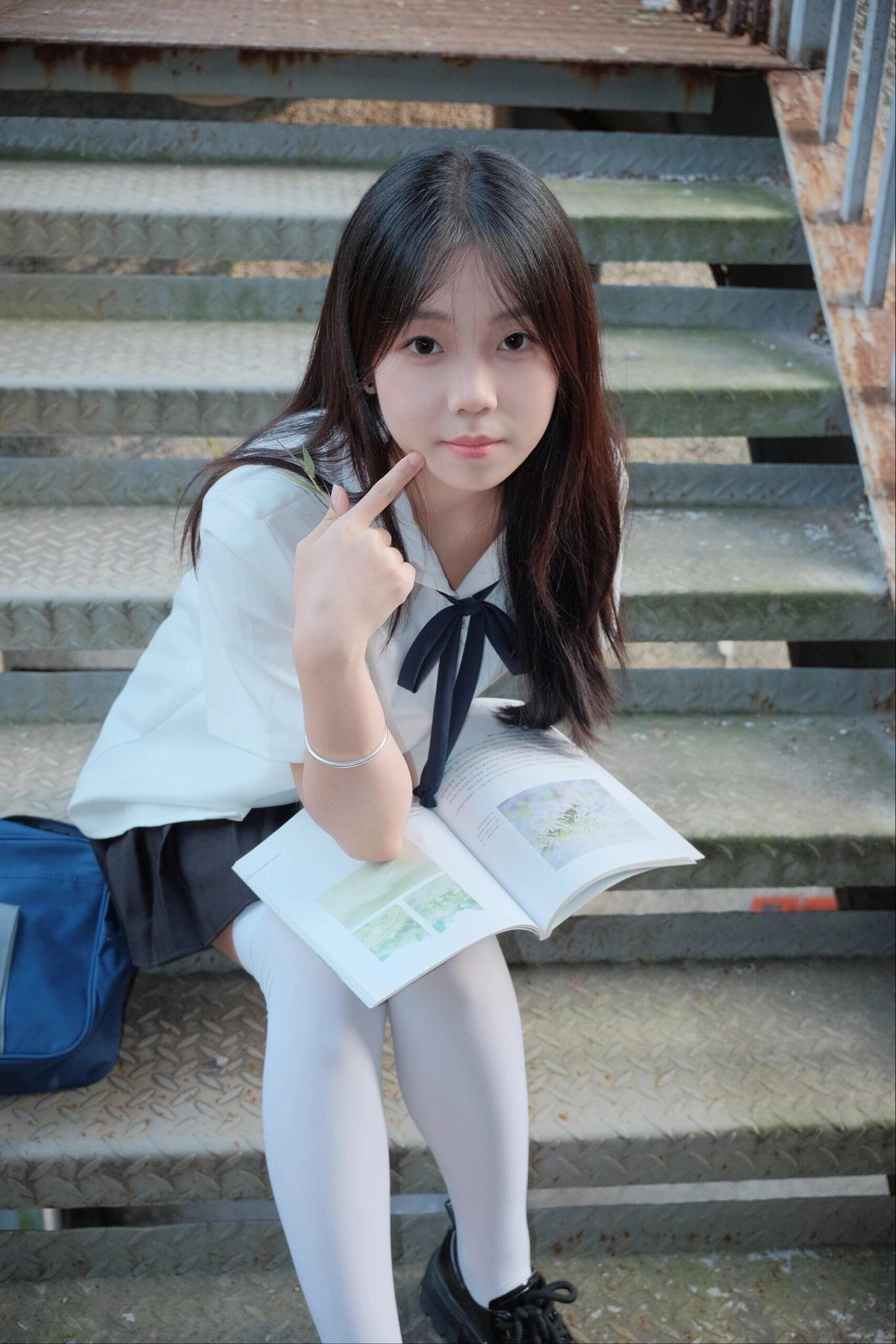 头发上有蓝弓的女孩指着一本书。