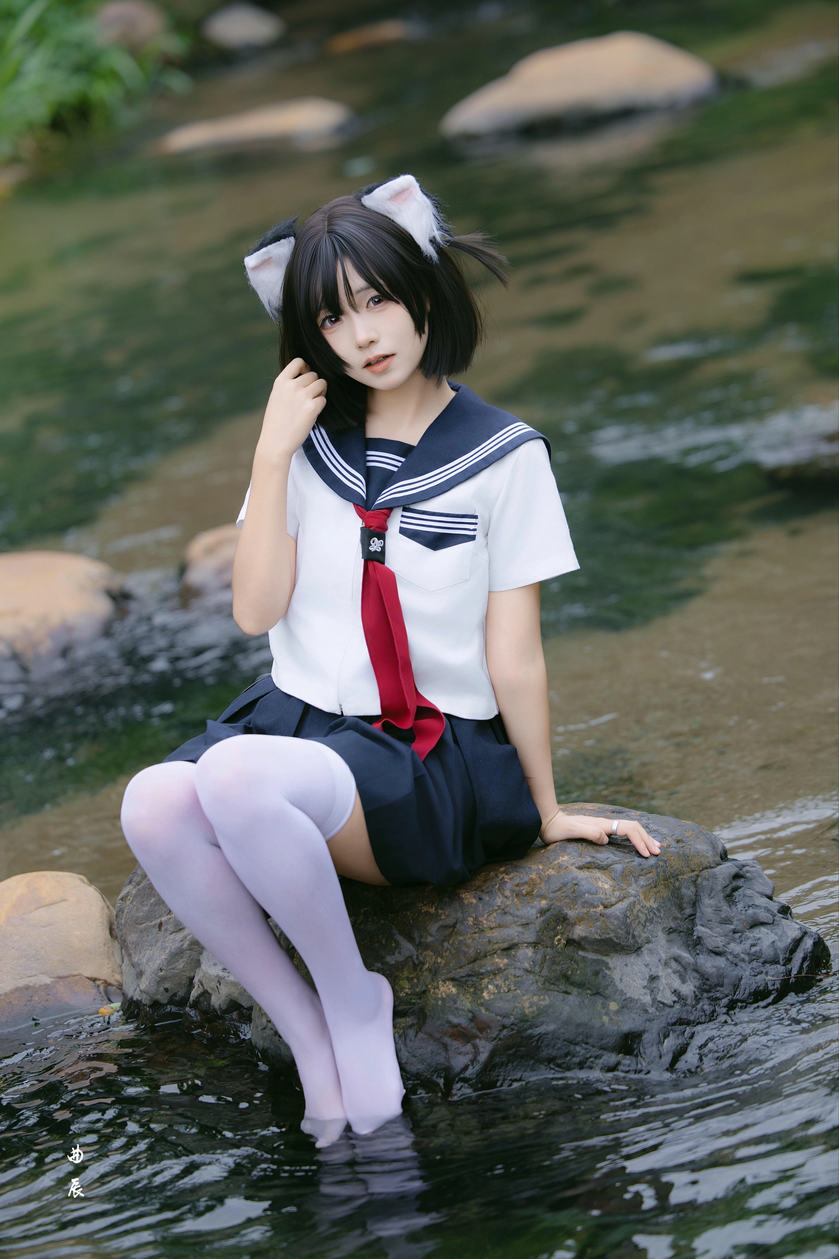 穿着红色衬衫的女孩坐在一块石头上。