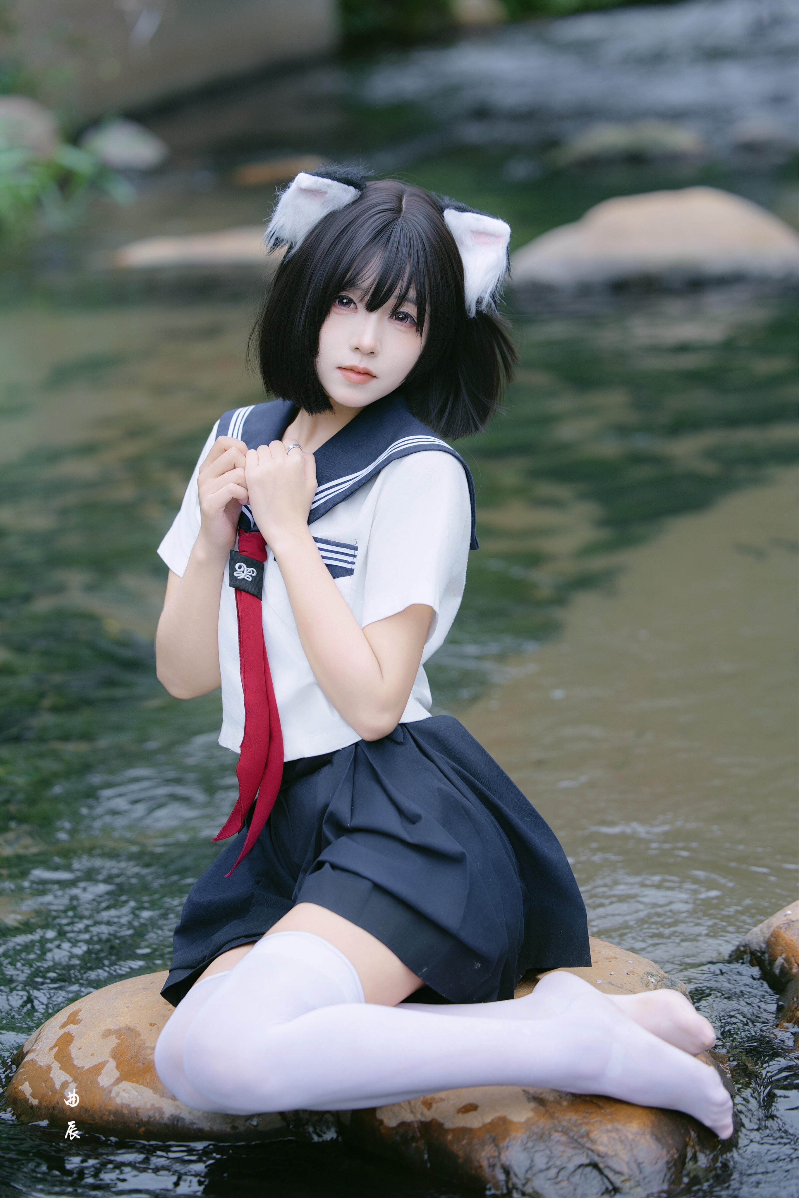 穿着红色衬衫的女孩坐在一块石头上。