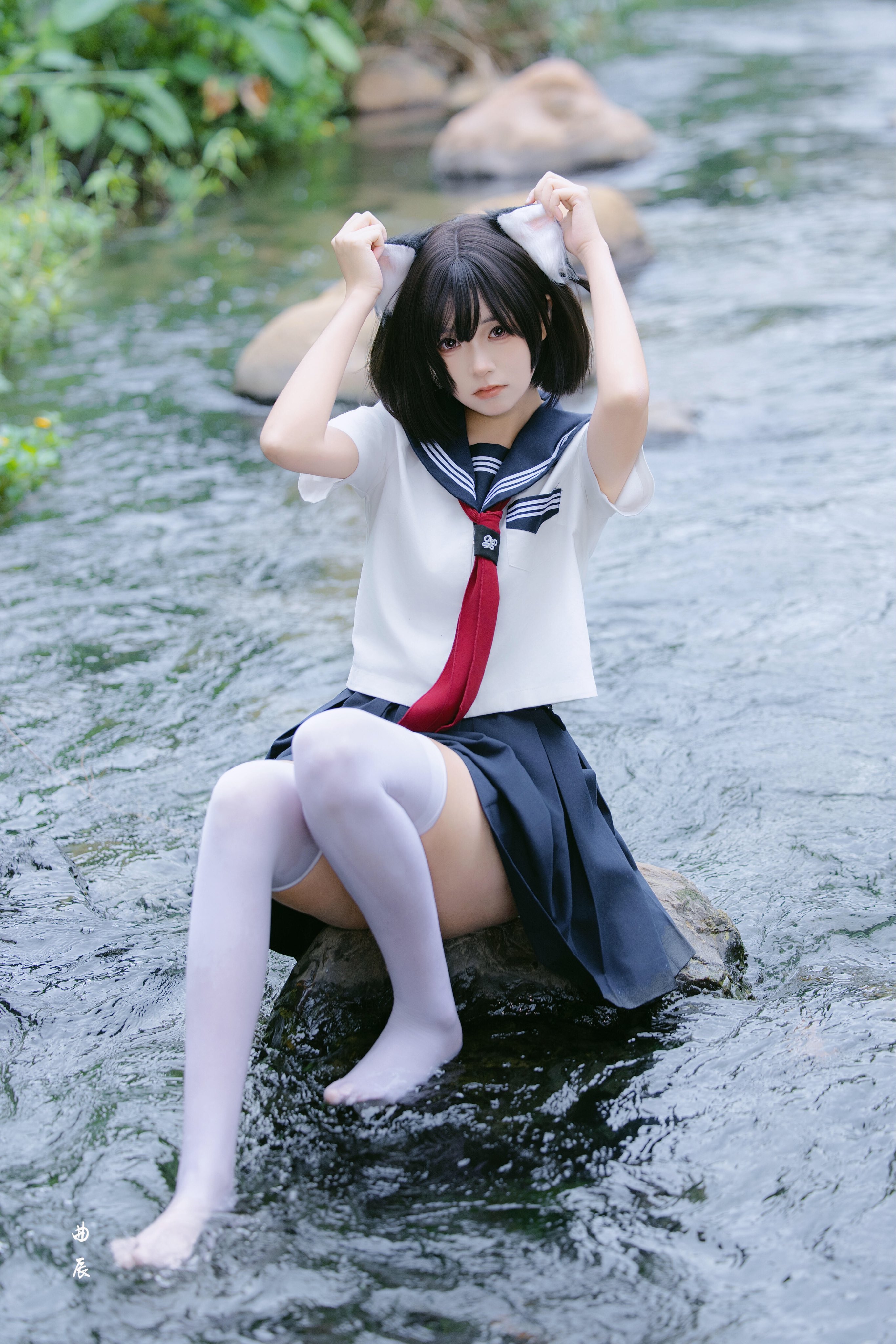 穿着红色衬衫的女孩坐在一块石头上。