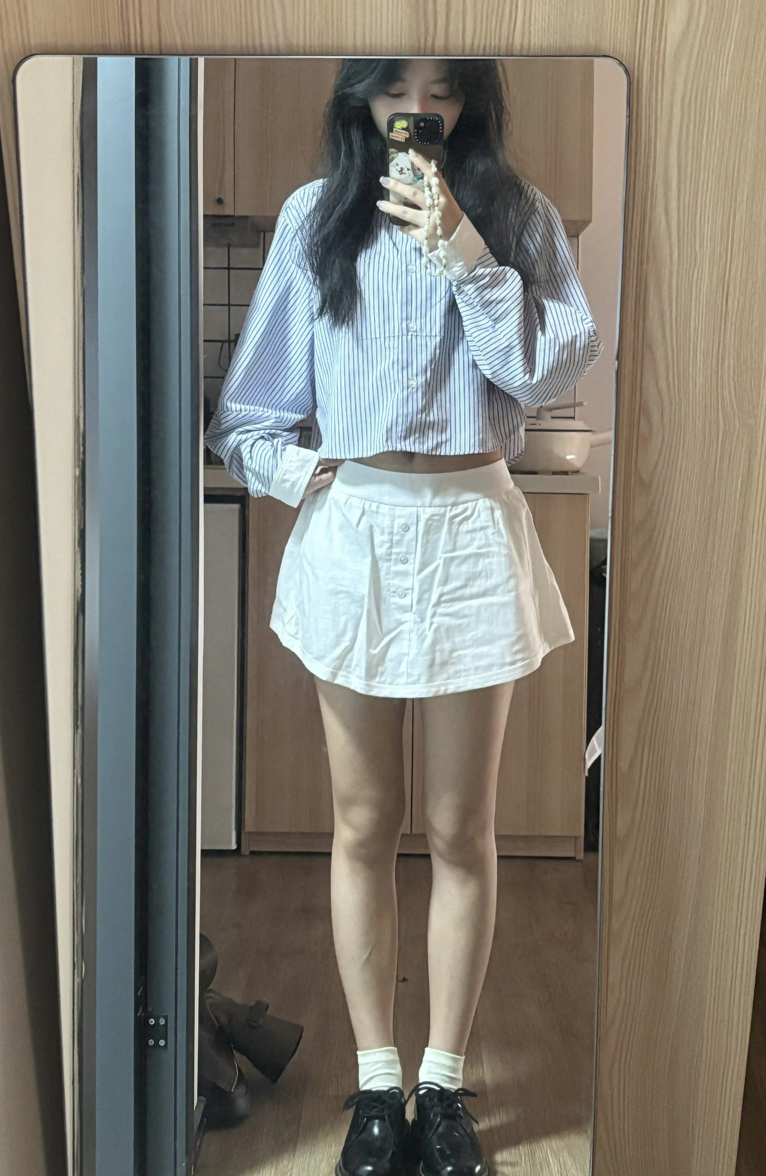 一位穿着白色裙子和蓝色衬衫的女人拍了一张自拍。