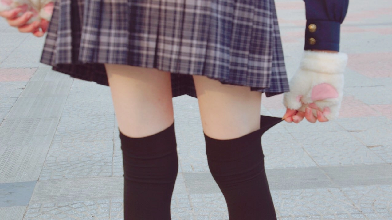 穿着裙子和黑色袜子的女人正在抱着一个白色的狗。