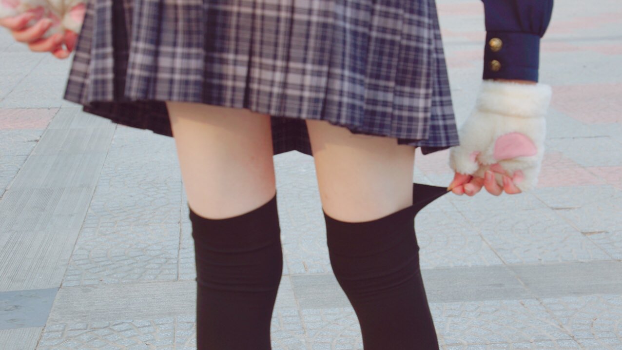 穿着裙子和黑色袜子的女人正在抱着一个白色的狗。