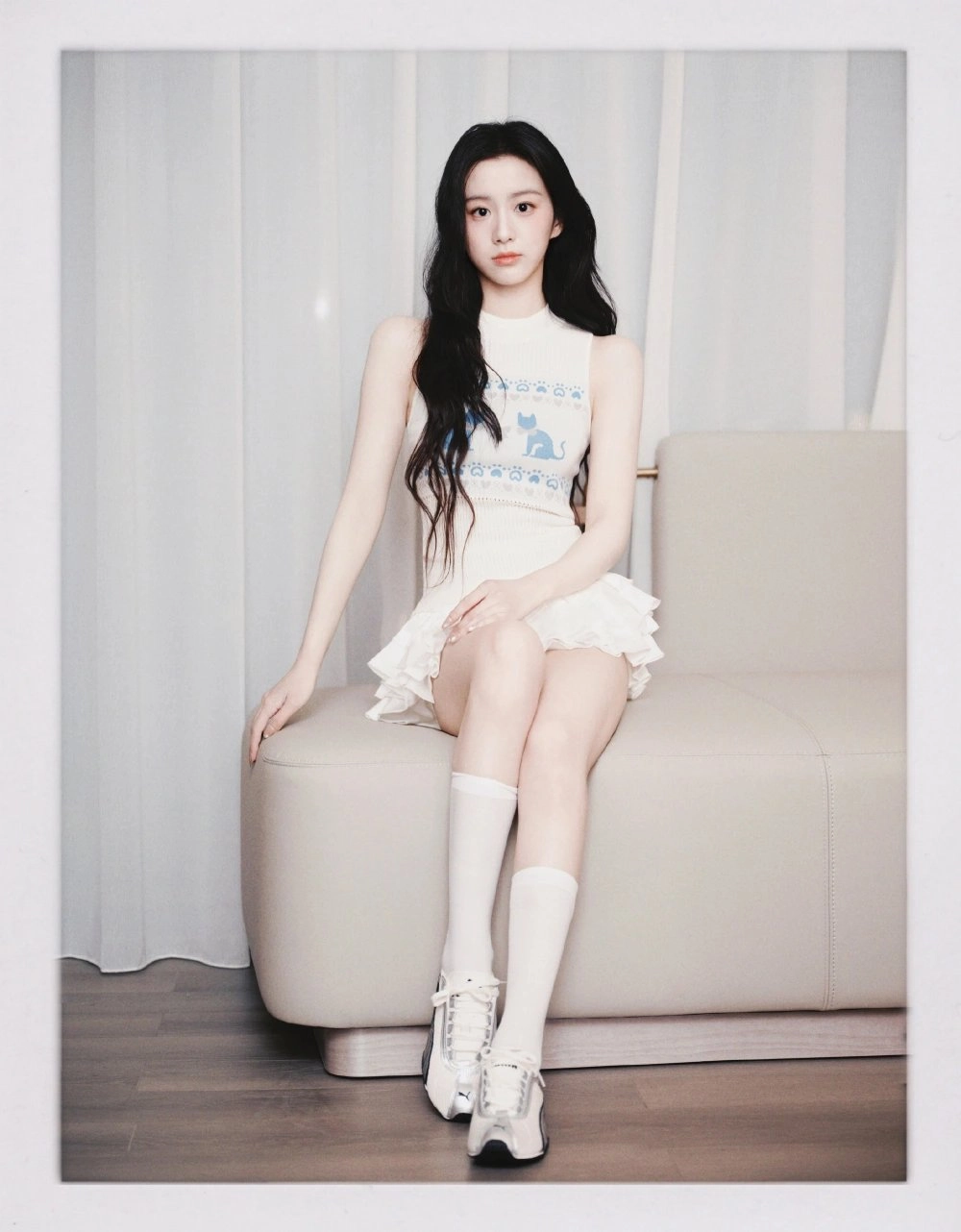 穿着白色裙子和白袜子的女孩坐在沙发上。