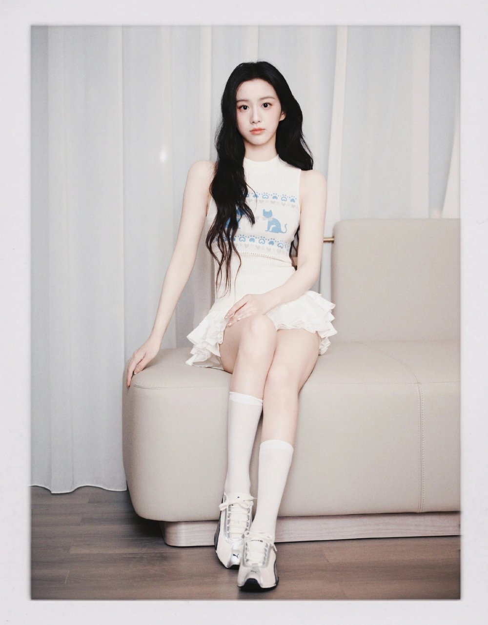 穿着白色裙子和白袜子的女孩坐在沙发上。