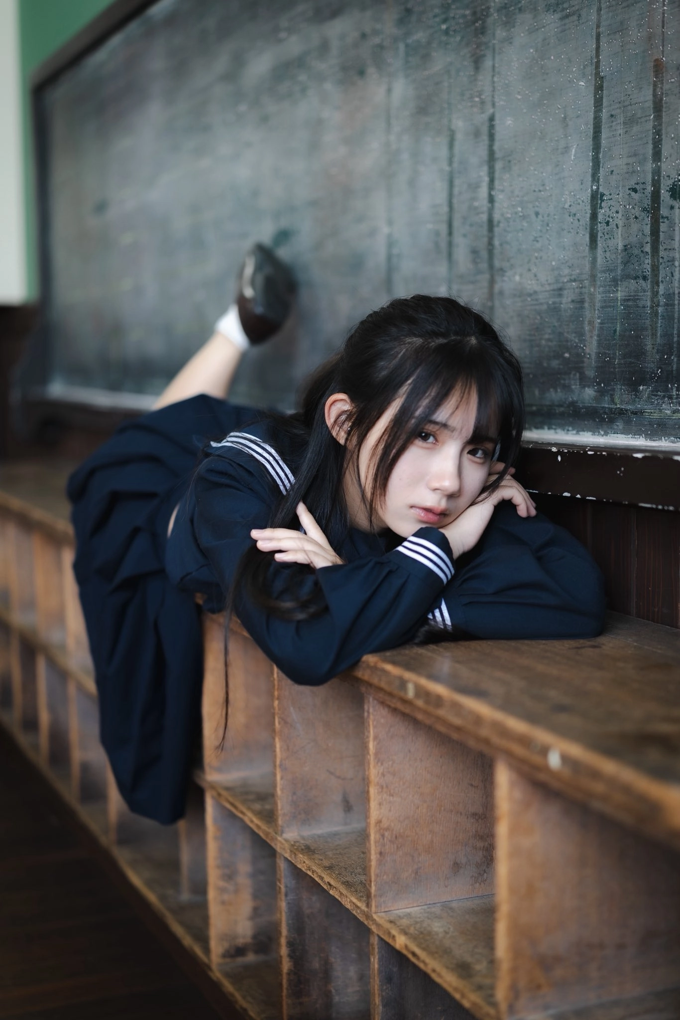 一位穿着蓝色衬衫和黑色衬衫的女孩坐在凳子上。