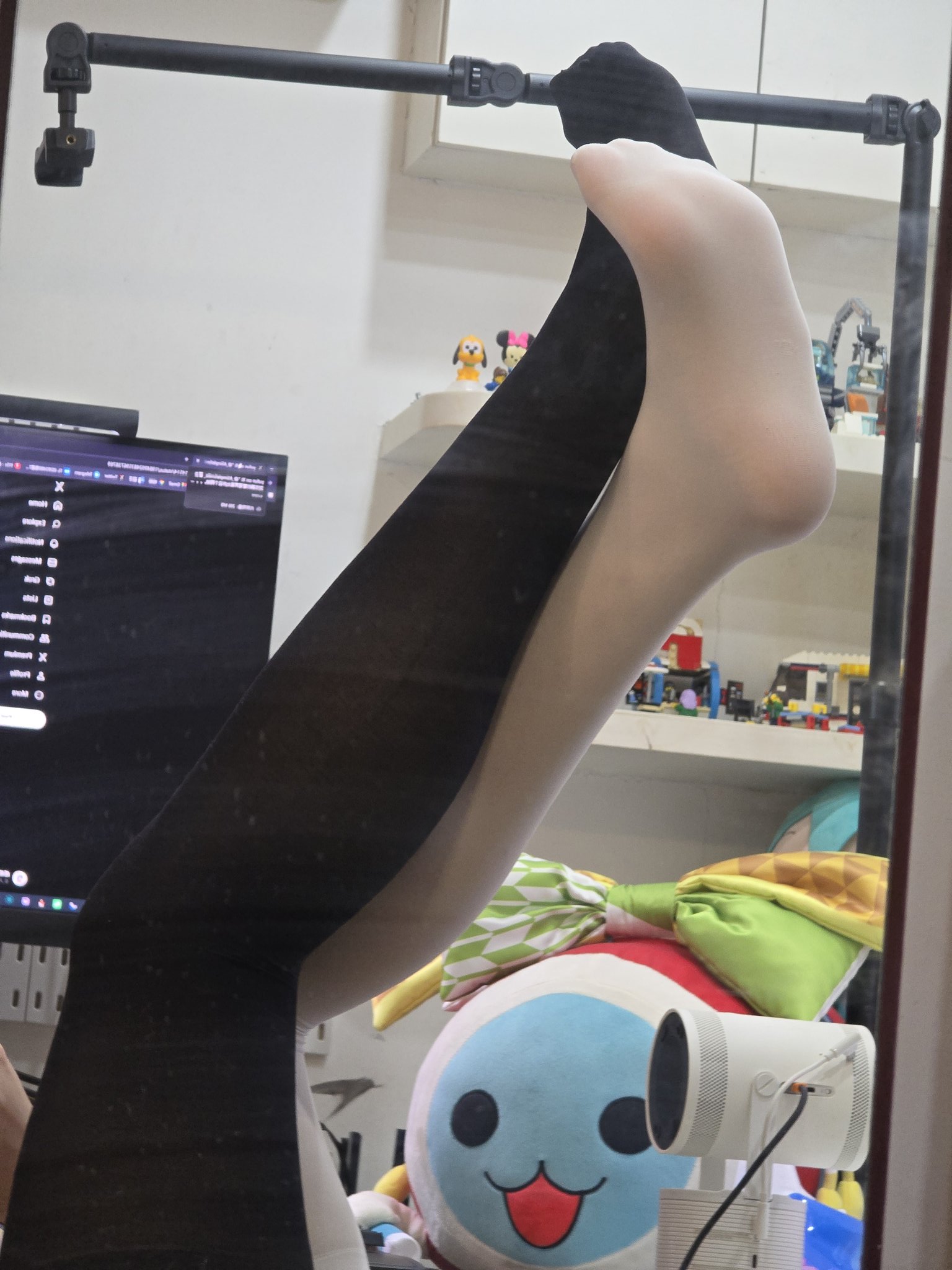 人的腿在镜子中可以看到,背后有一个电脑监视器。