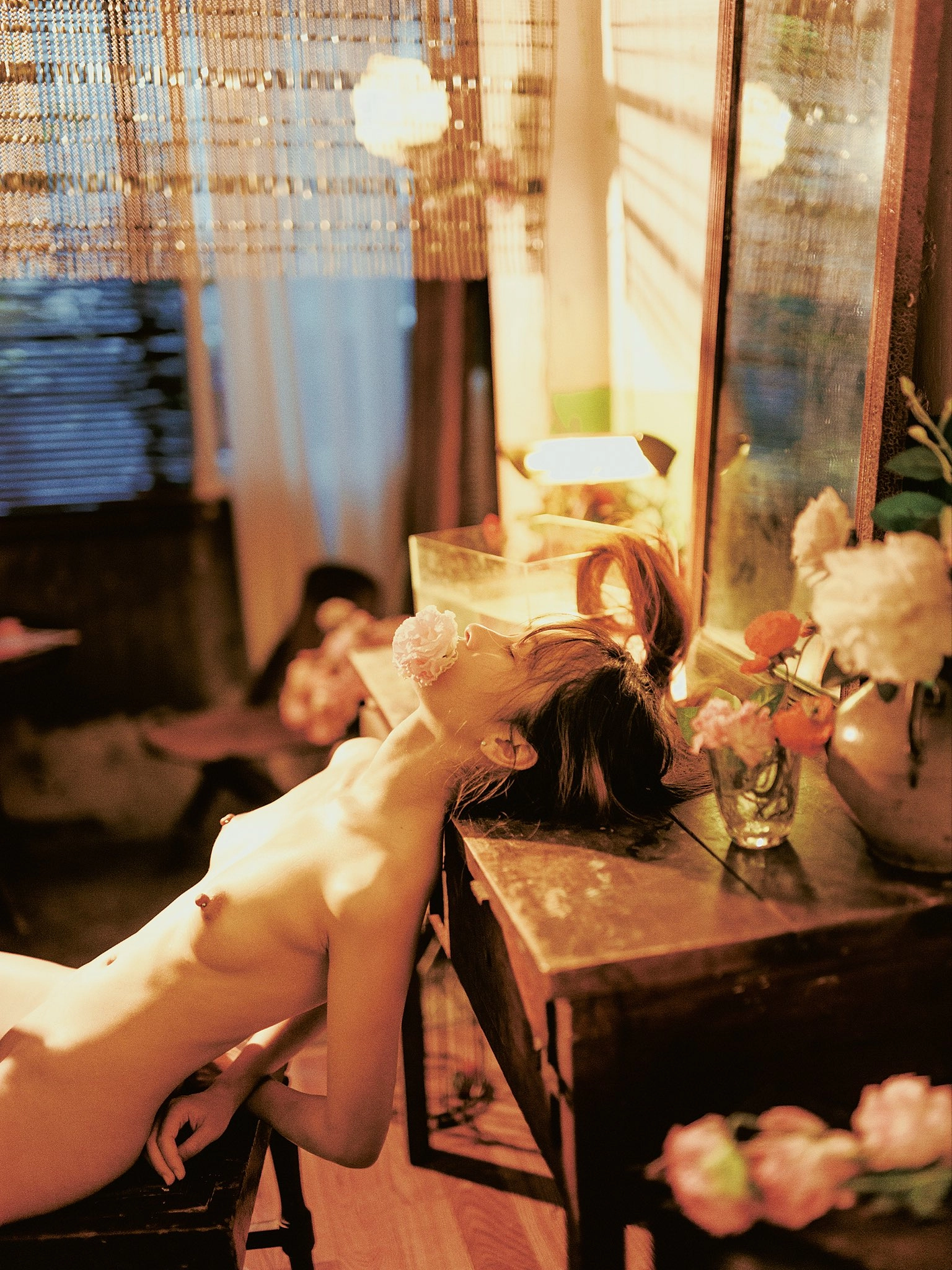 女人嘴里有一朵粉红色的花,躺在桌子上。