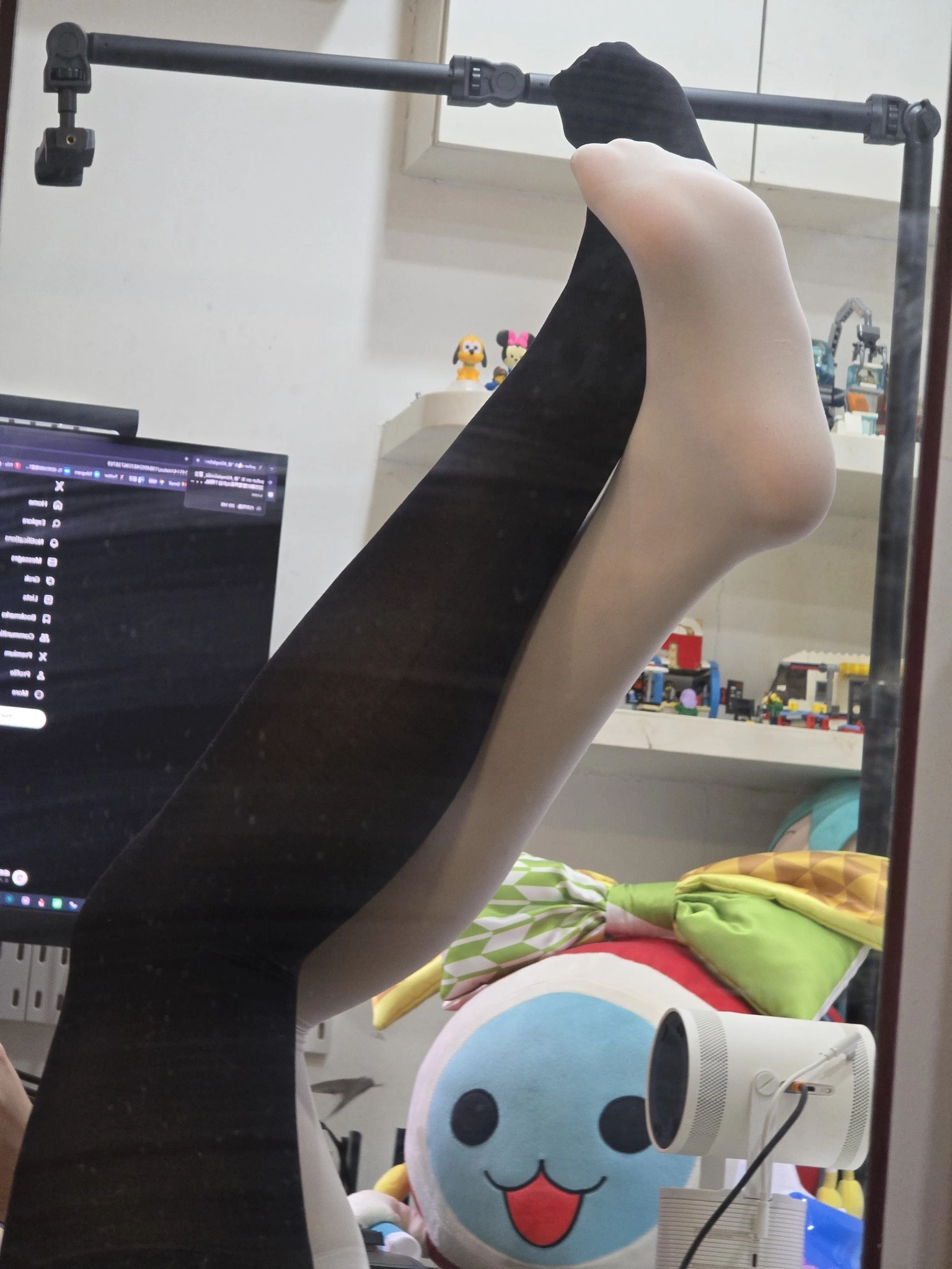 人的腿在镜子中可以看到,背后有一个电脑监视器。