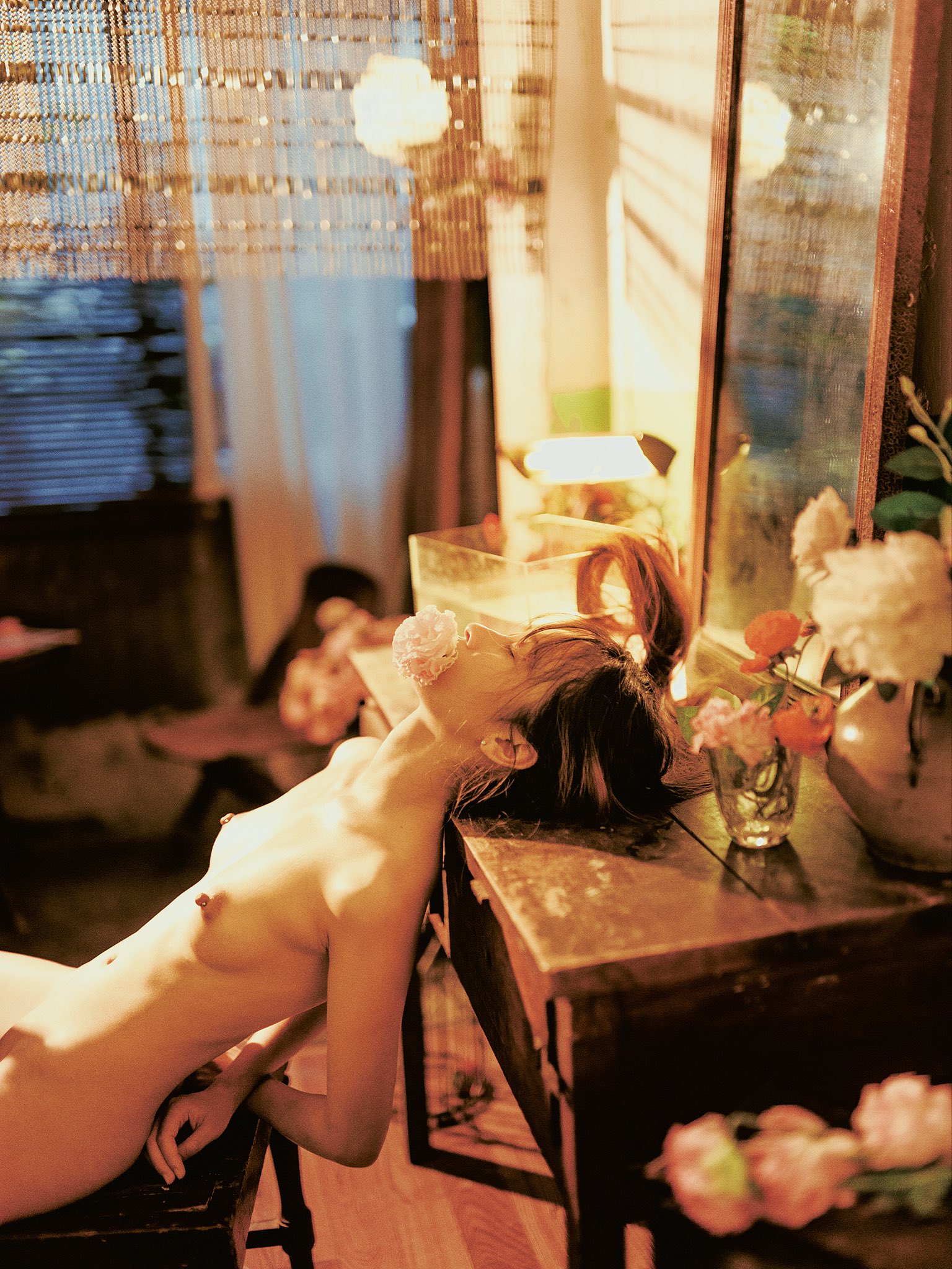 女人嘴里有一朵粉红色的花,躺在桌子上。