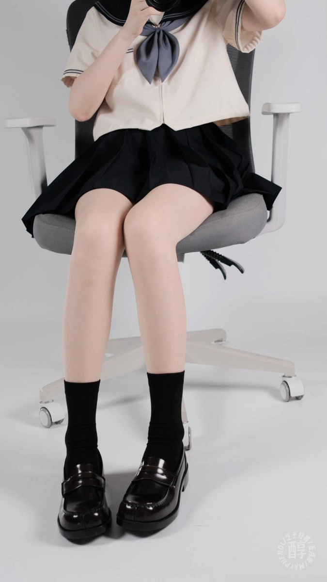 穿着黑袜子和黑裙子的女人坐在椅子上。