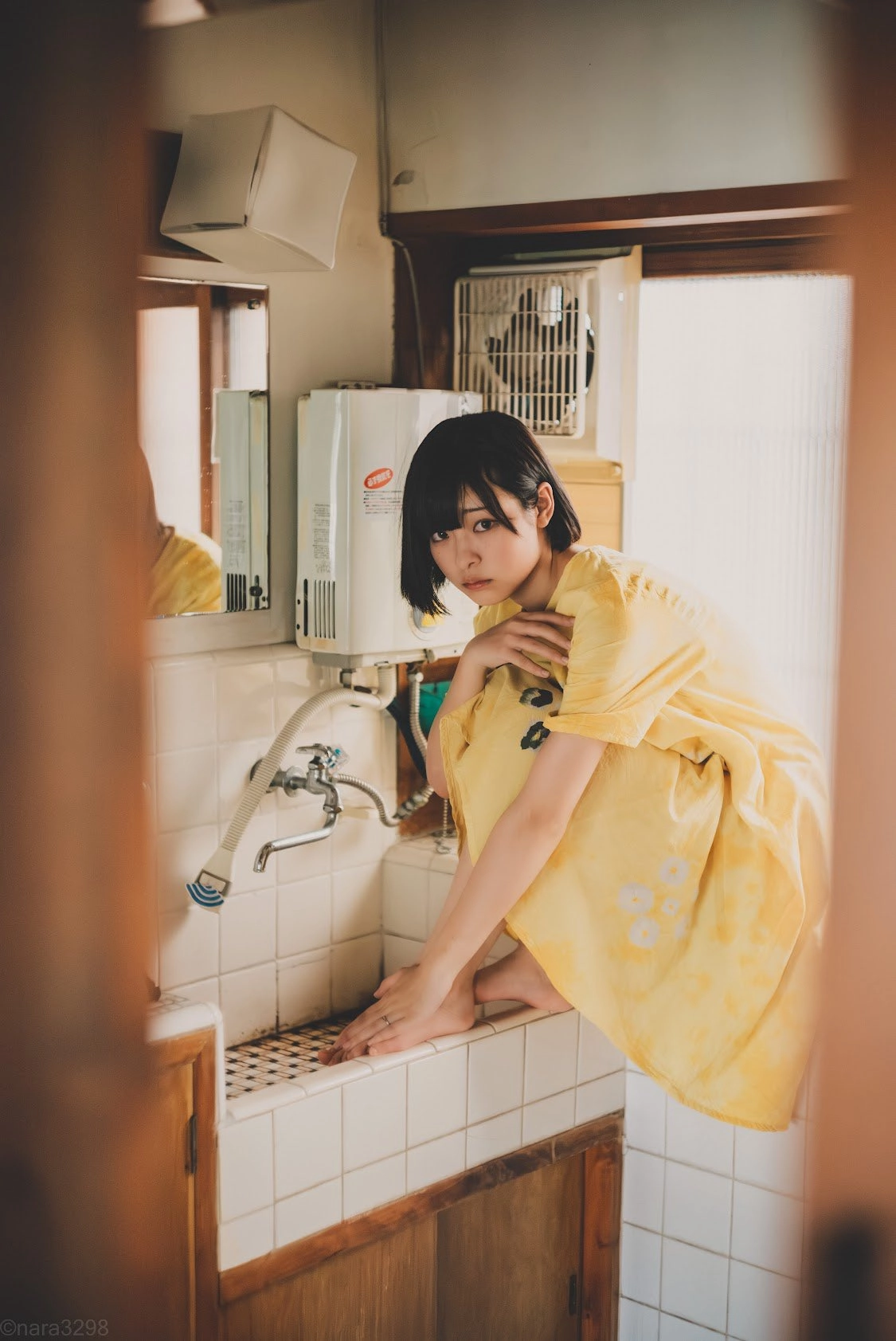 短发和一件黄色衬衫的女人站在一个水槽前面。