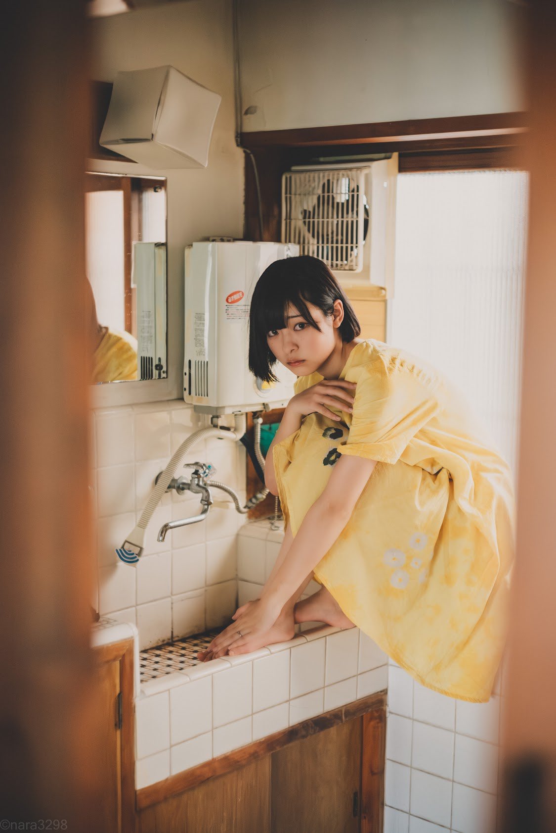 短发和一件黄色衬衫的女人站在一个水槽前面。