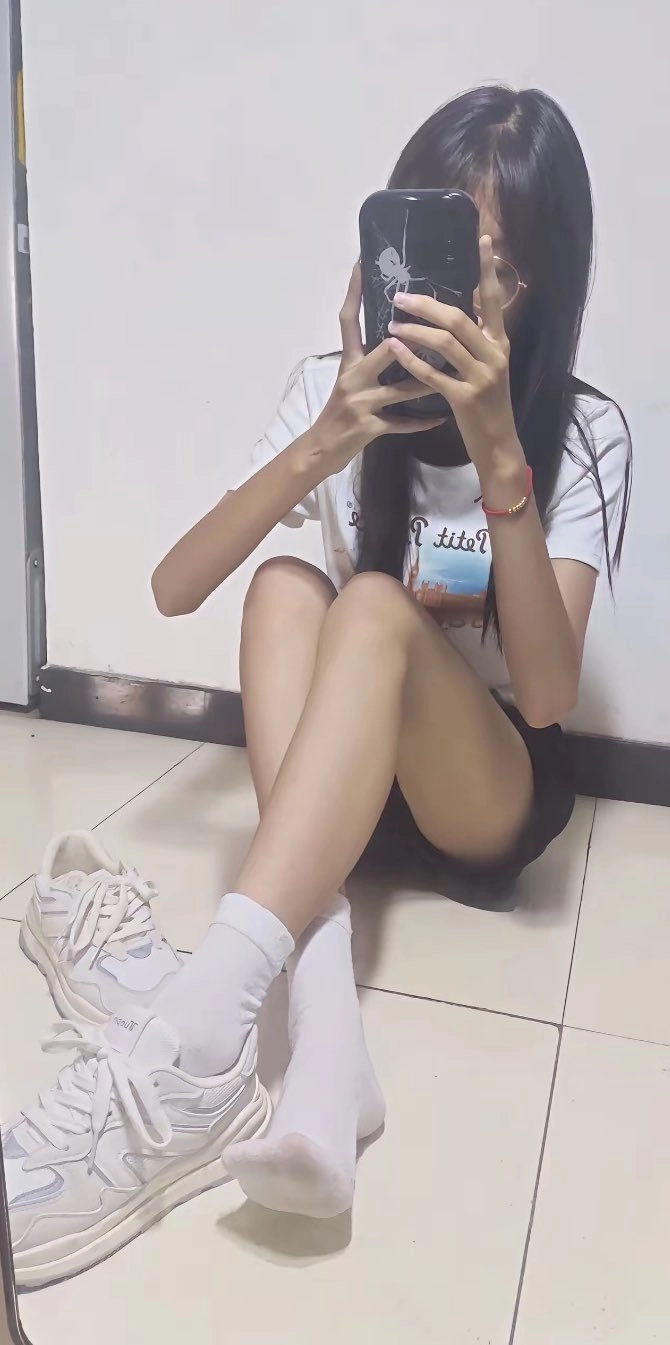 女人坐在地板上,拿着手机。