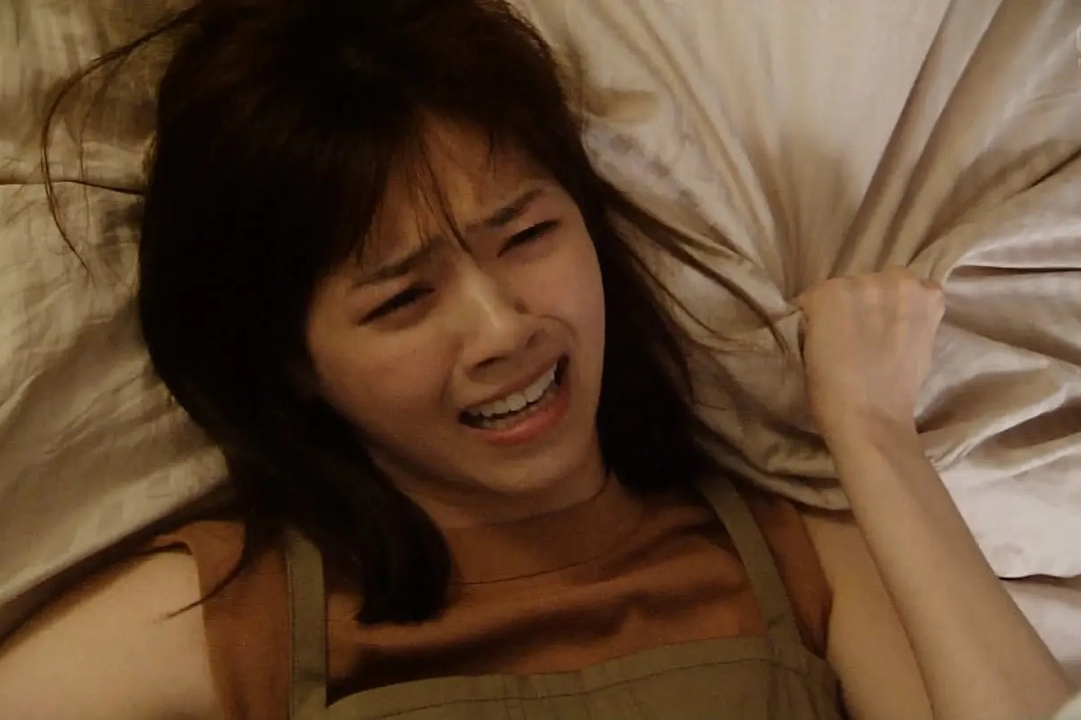 穿着棕色衬衫的女人躺在床上。