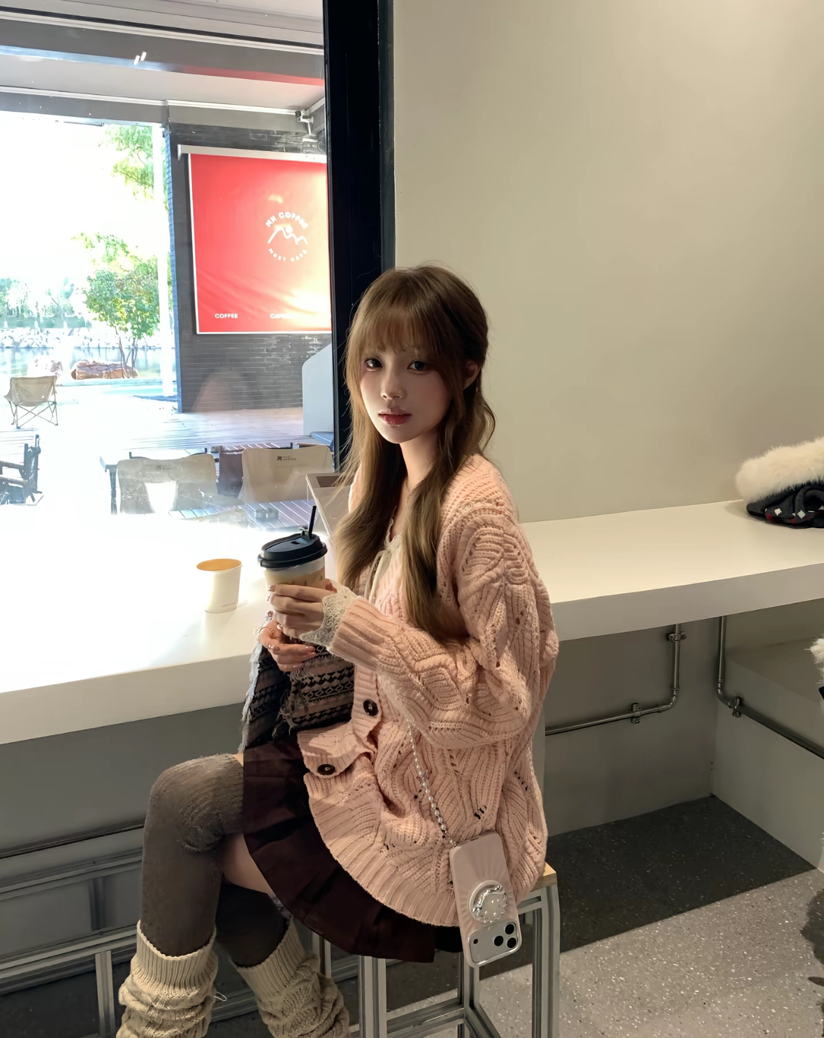 穿着粉红色衬衫的女人拿着一杯咖啡。