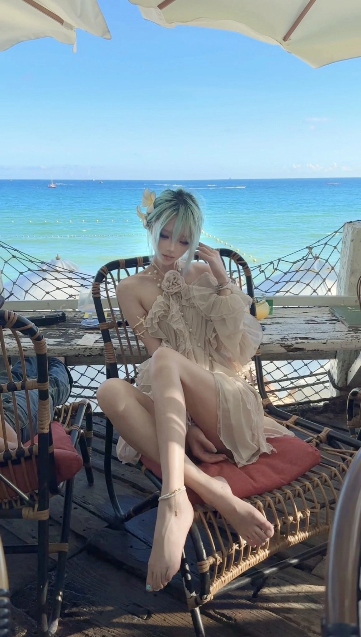 一位穿着白色衣服的女人坐在一把椅子上,俯瞰大海。