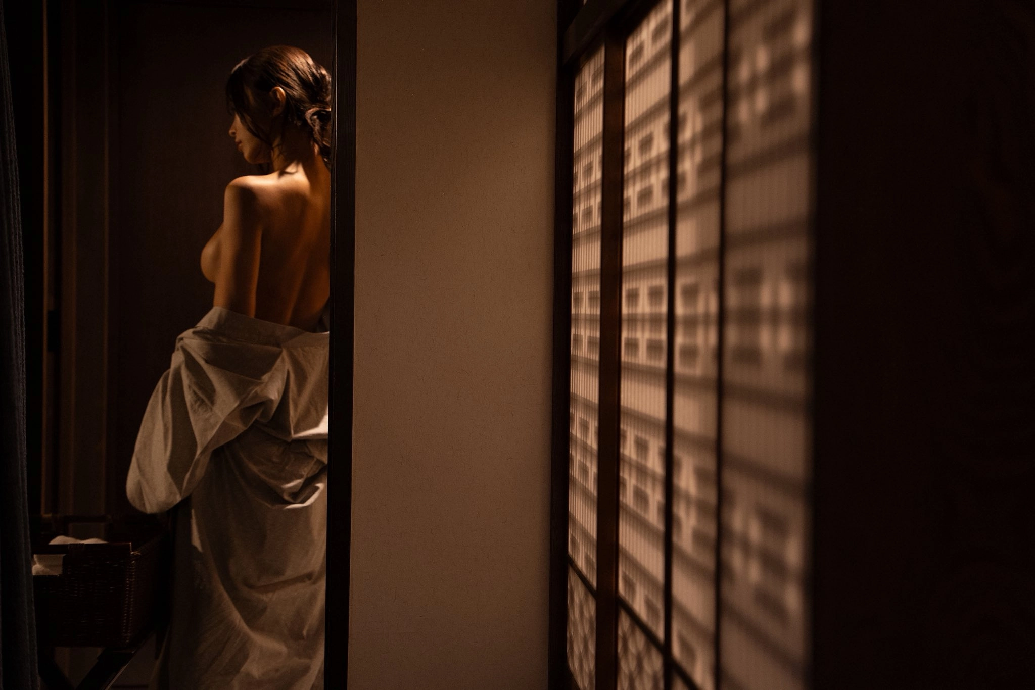 一位穿著白色衣服的女人站在有滑動門的房間裏。