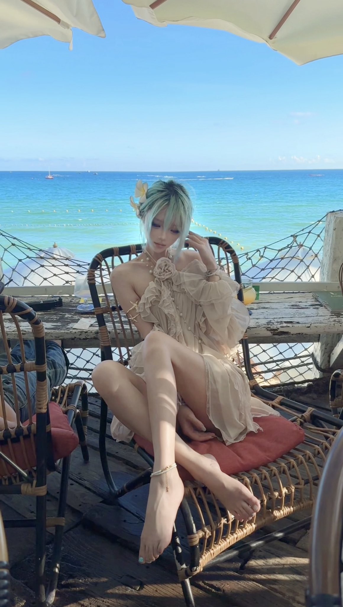 一位穿着白色衣服的女人坐在一把椅子上,俯瞰大海。