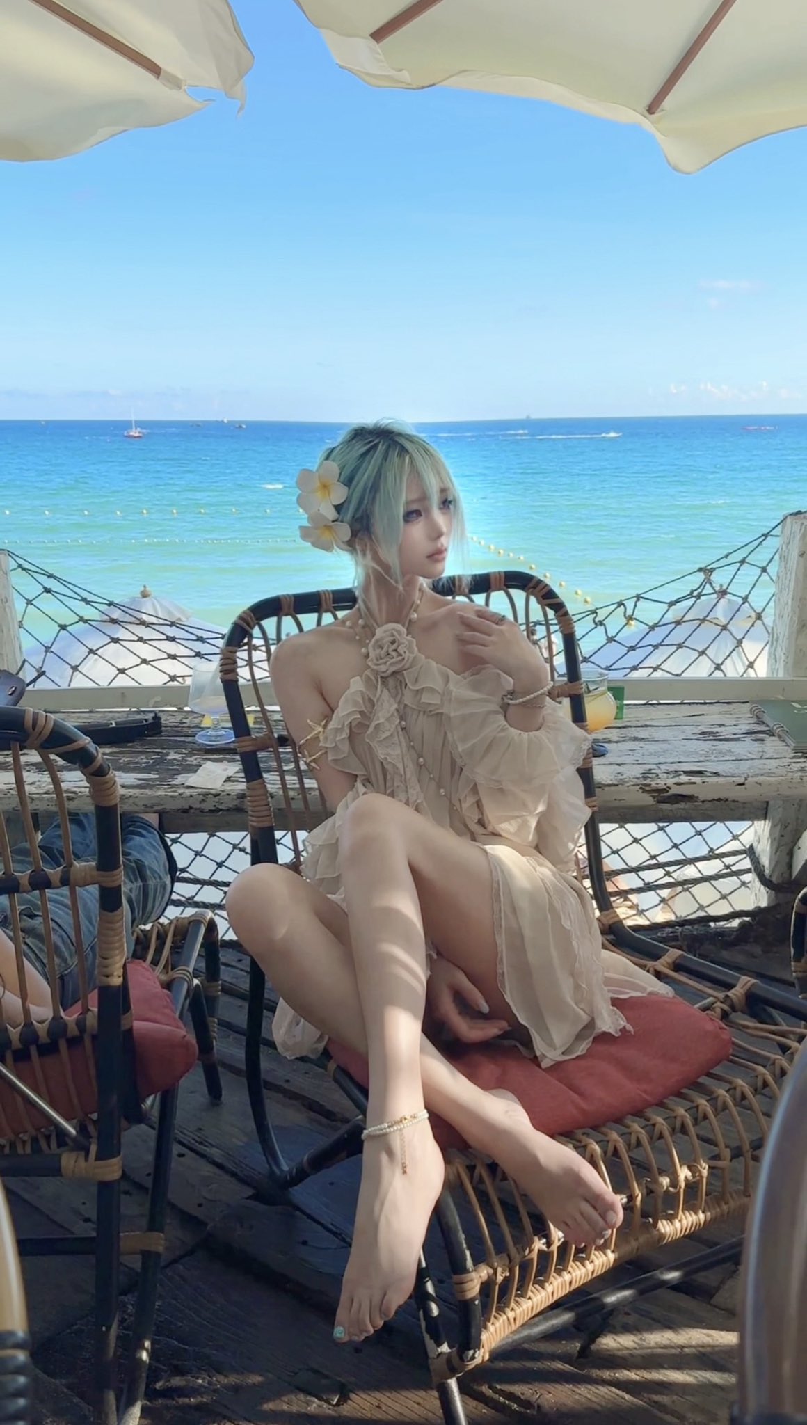 一位穿着白色衣服的女人坐在一把椅子上,俯瞰大海。