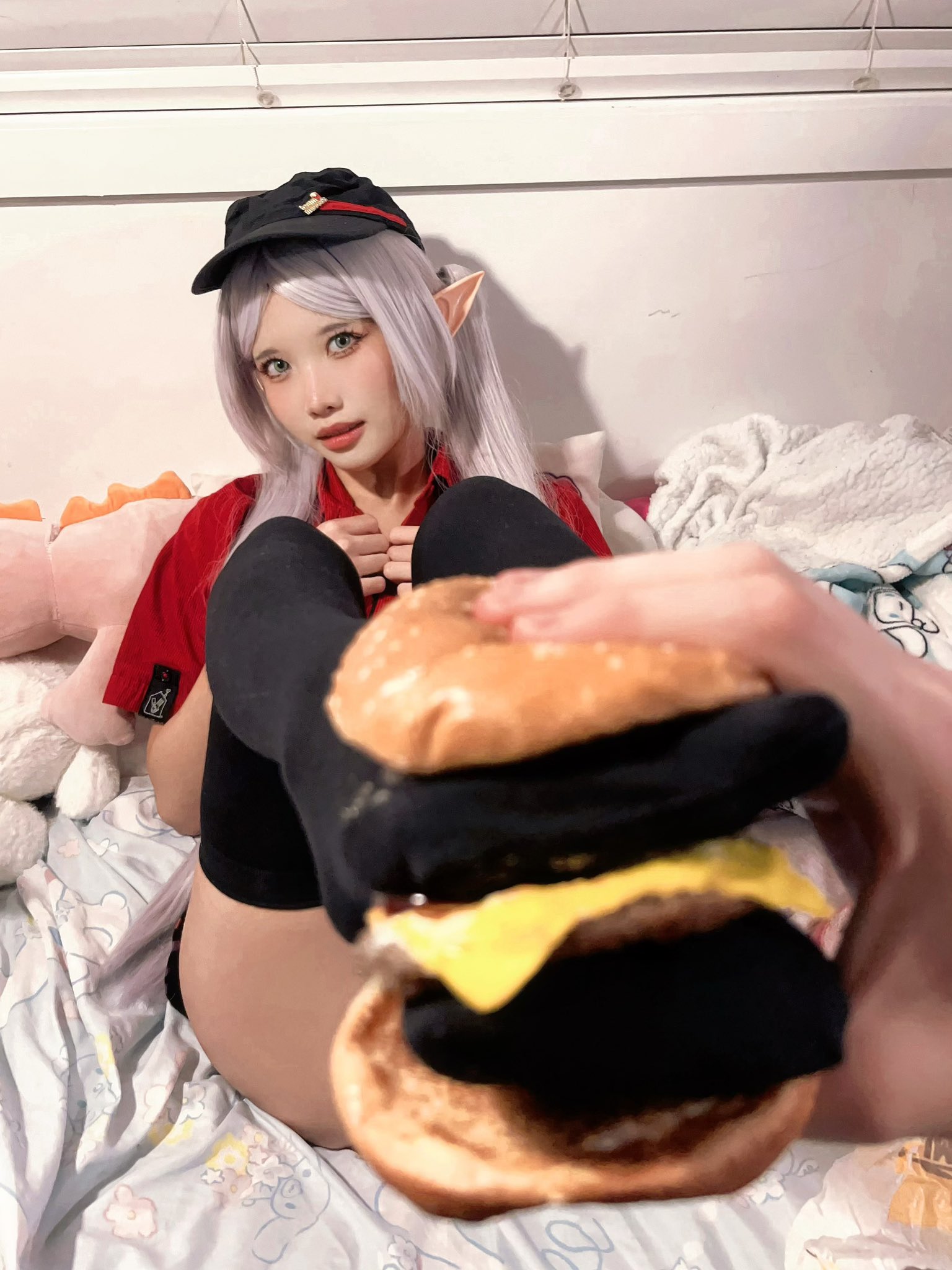 戴帽子的女孩在头上拿着一个汉堡。