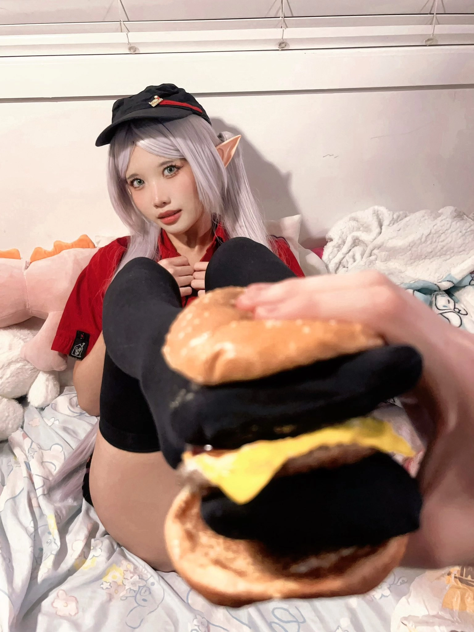 戴帽子的女孩在头上拿着一个汉堡。