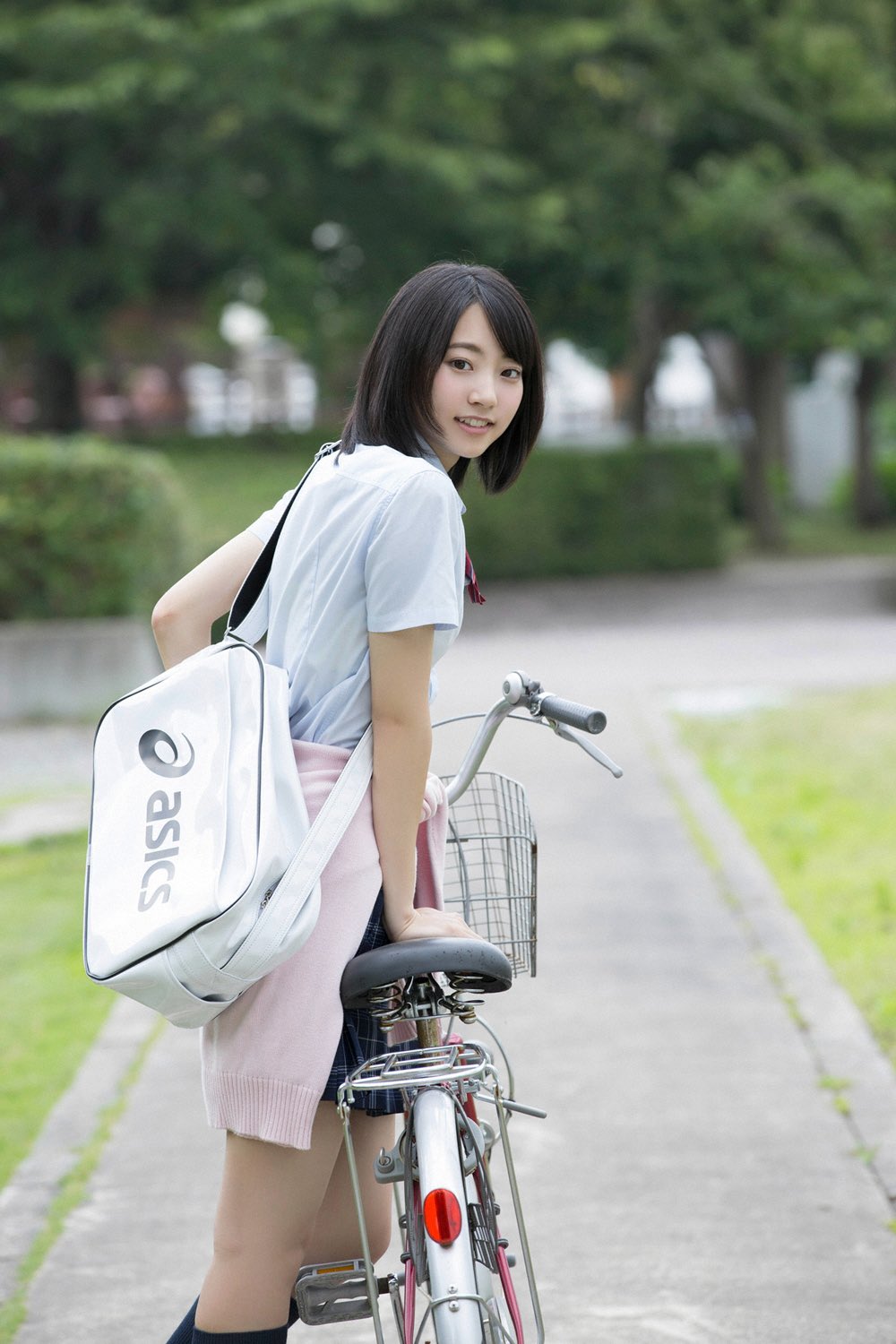 女人背上戴着一个弓和一个袋子骑着一辆自行车。