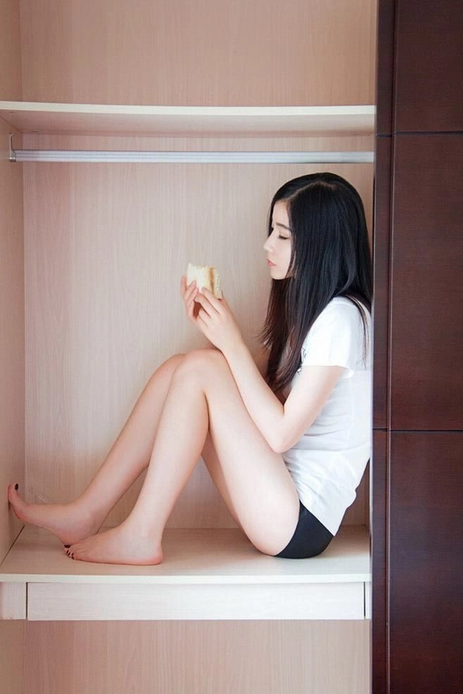 Người phụ nữ ngồi trong tủ quần áo ăn một chiếc bánh sandwich.