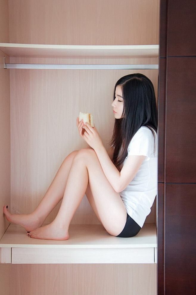 女人坐在衣柜里吃一顿三明治。