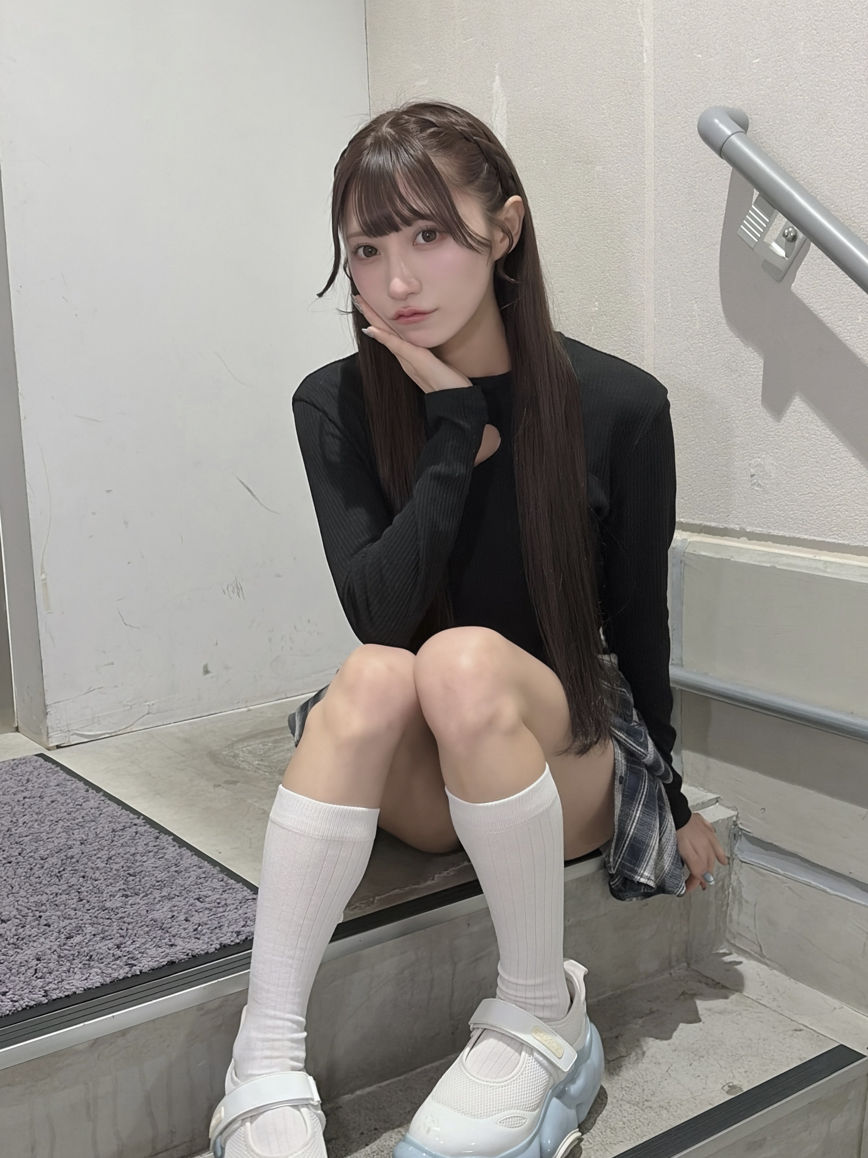 长头发和黑衬衫的女孩坐在一个步骤上。