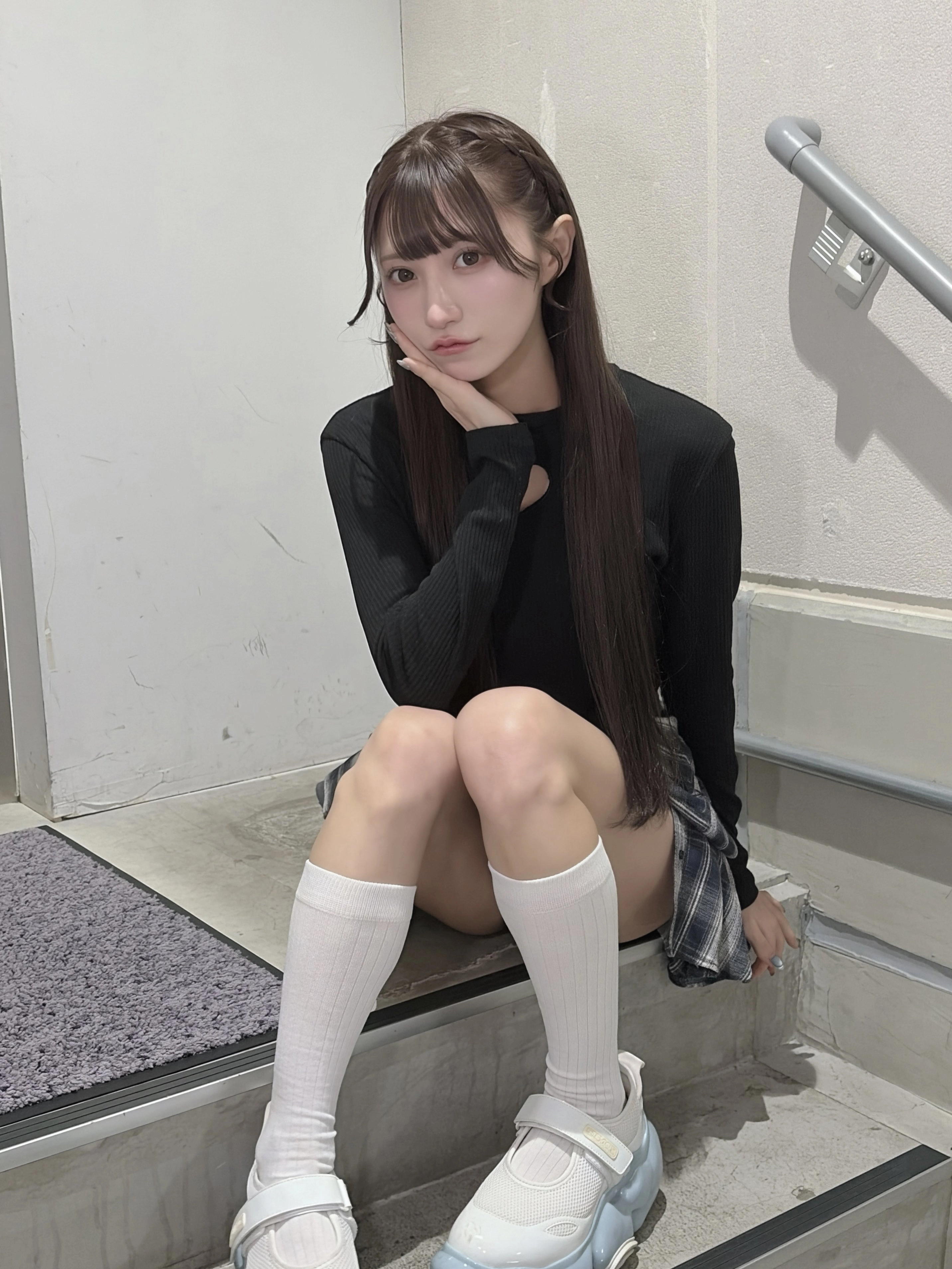 长头发和黑衬衫的女孩坐在一个步骤上。