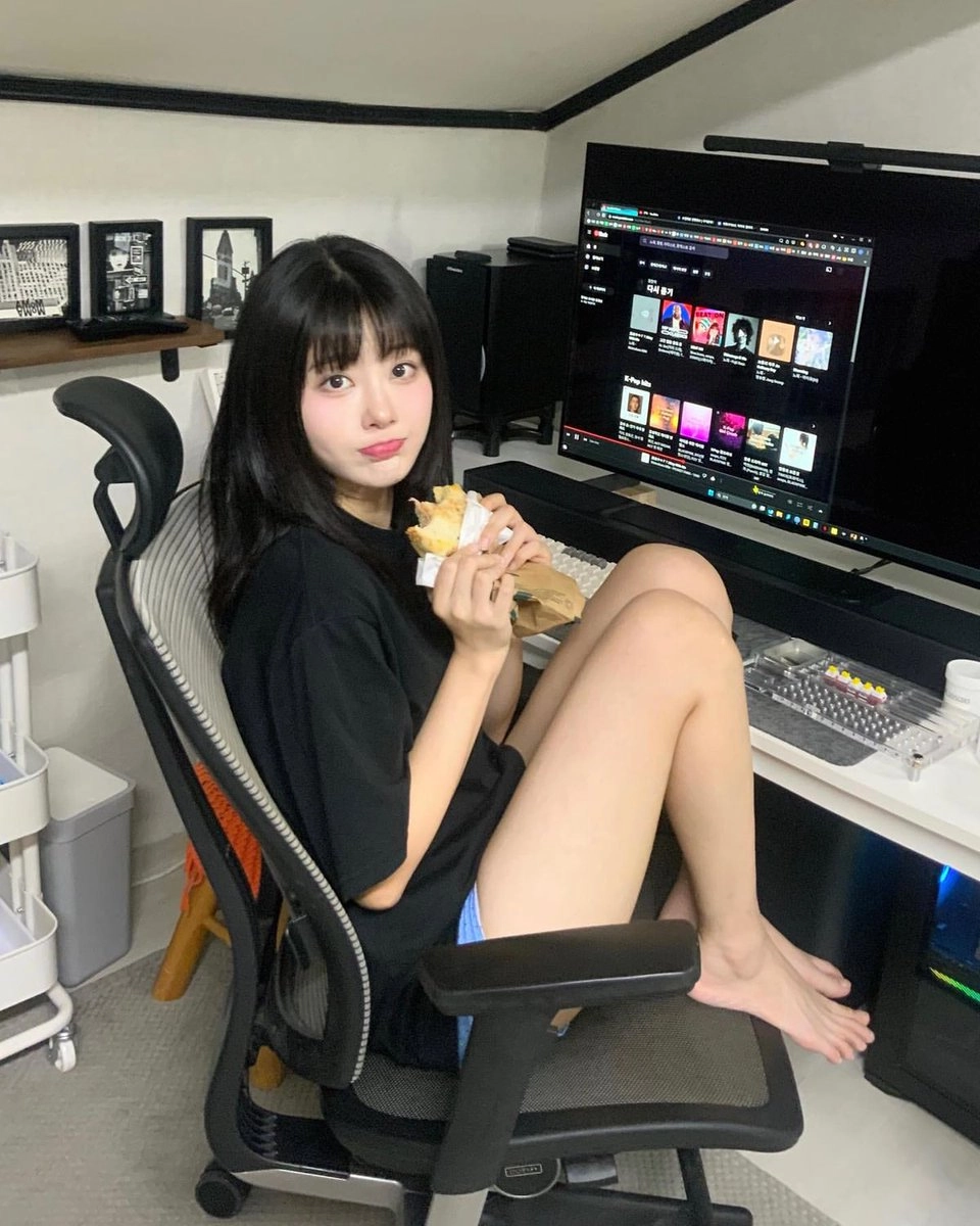 女人在电脑前坐在椅子上吃一顿三明治。