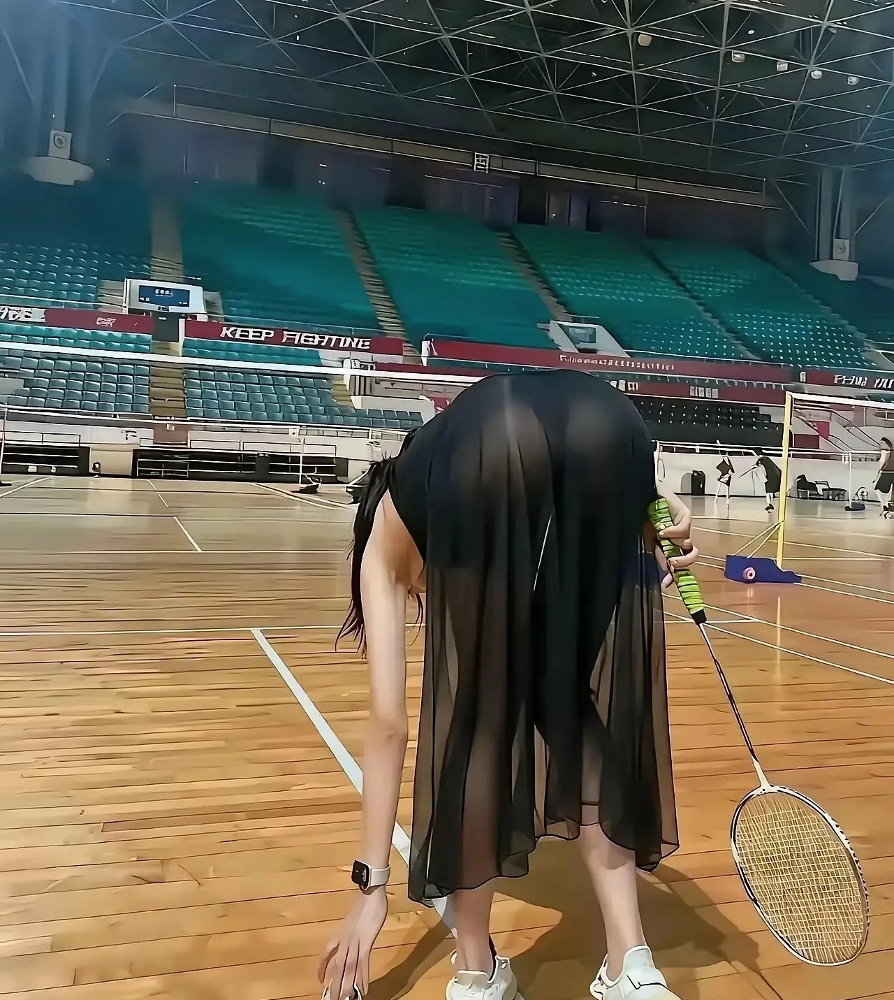 女人向前倾斜,拿起一根网球架。