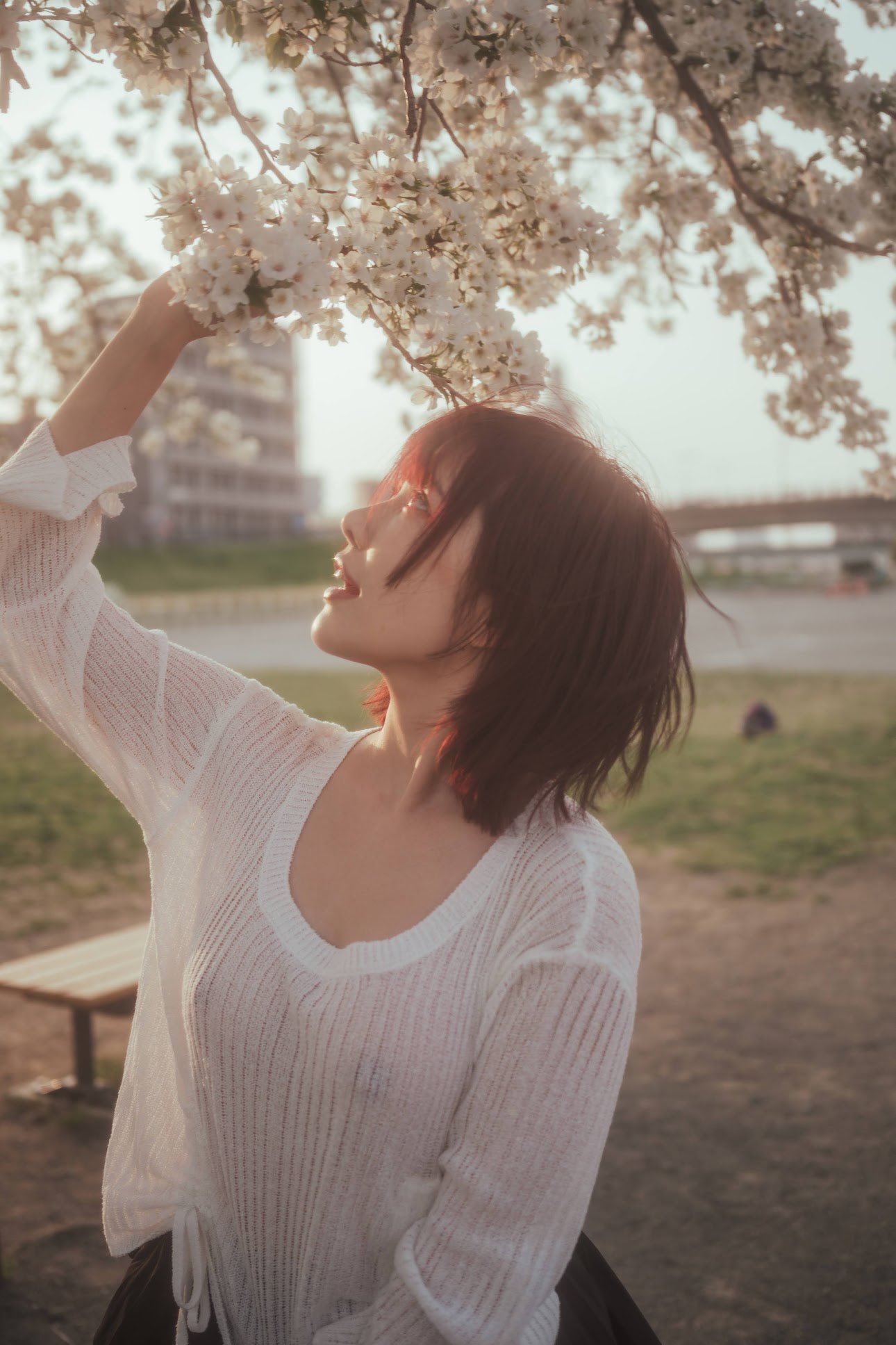 红头发和白衬衫的女人闻到鲜花。