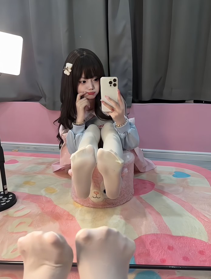 女孩坐在粉红色的地毯上,拿着手机。