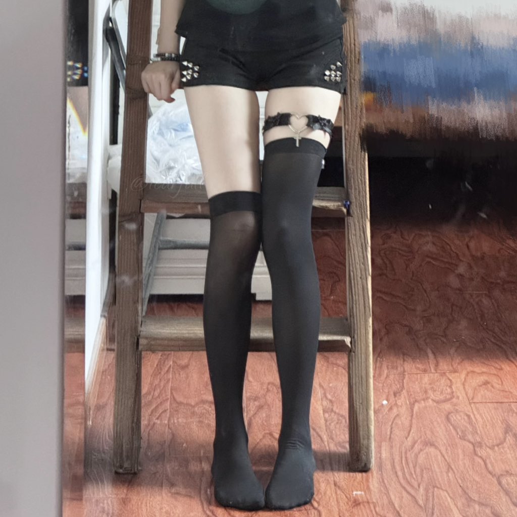 一位穿着黑色短裤和黑袜子的女人站在椅子上。