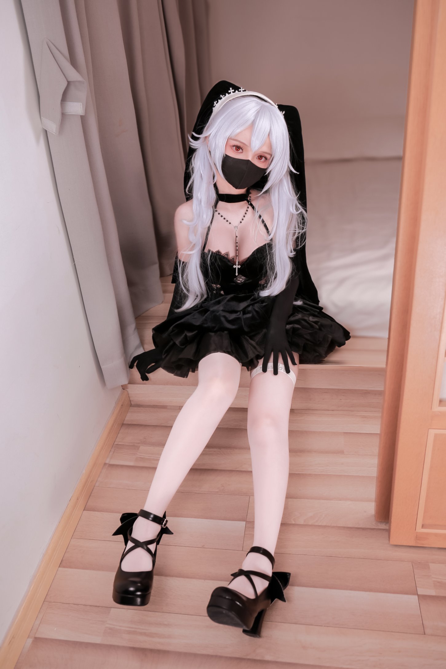 一位穿着黑面具和黑裙子的女人坐在楼梯上。