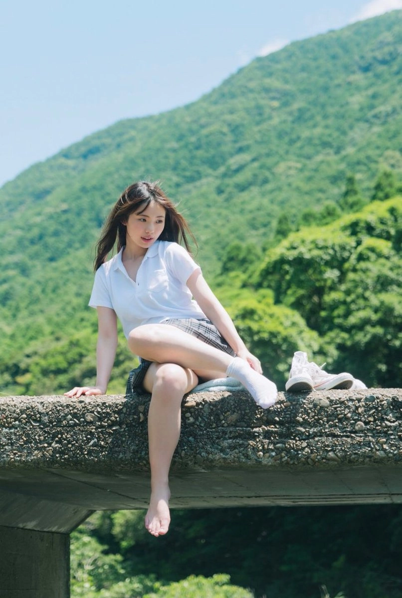 穿着白色衬衫和裙子的女人坐在岩石上。