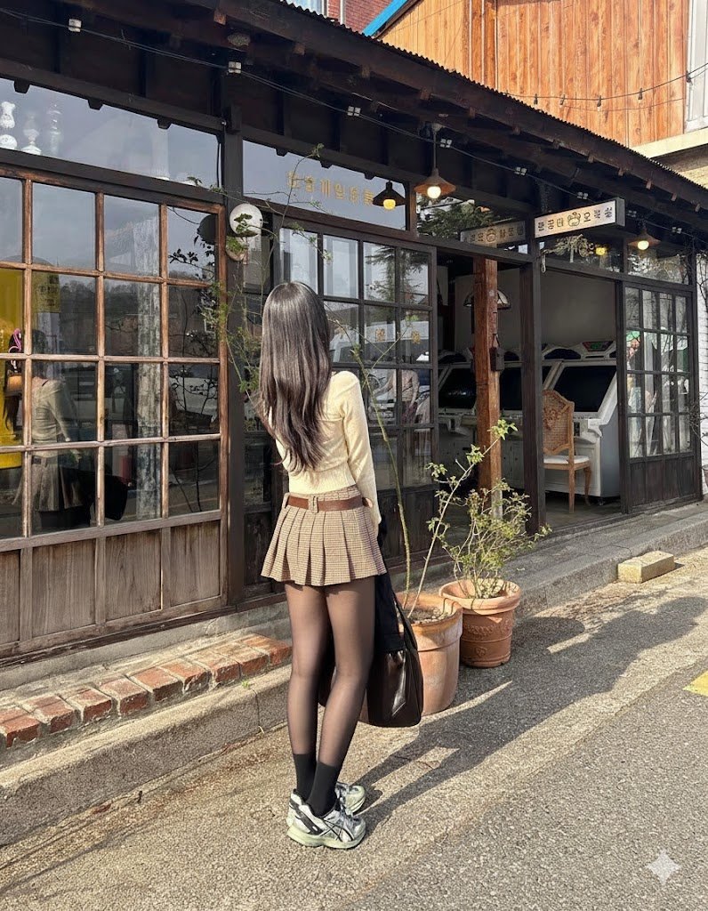 穿着棕色裙子和黑色外套的女人走在街上。