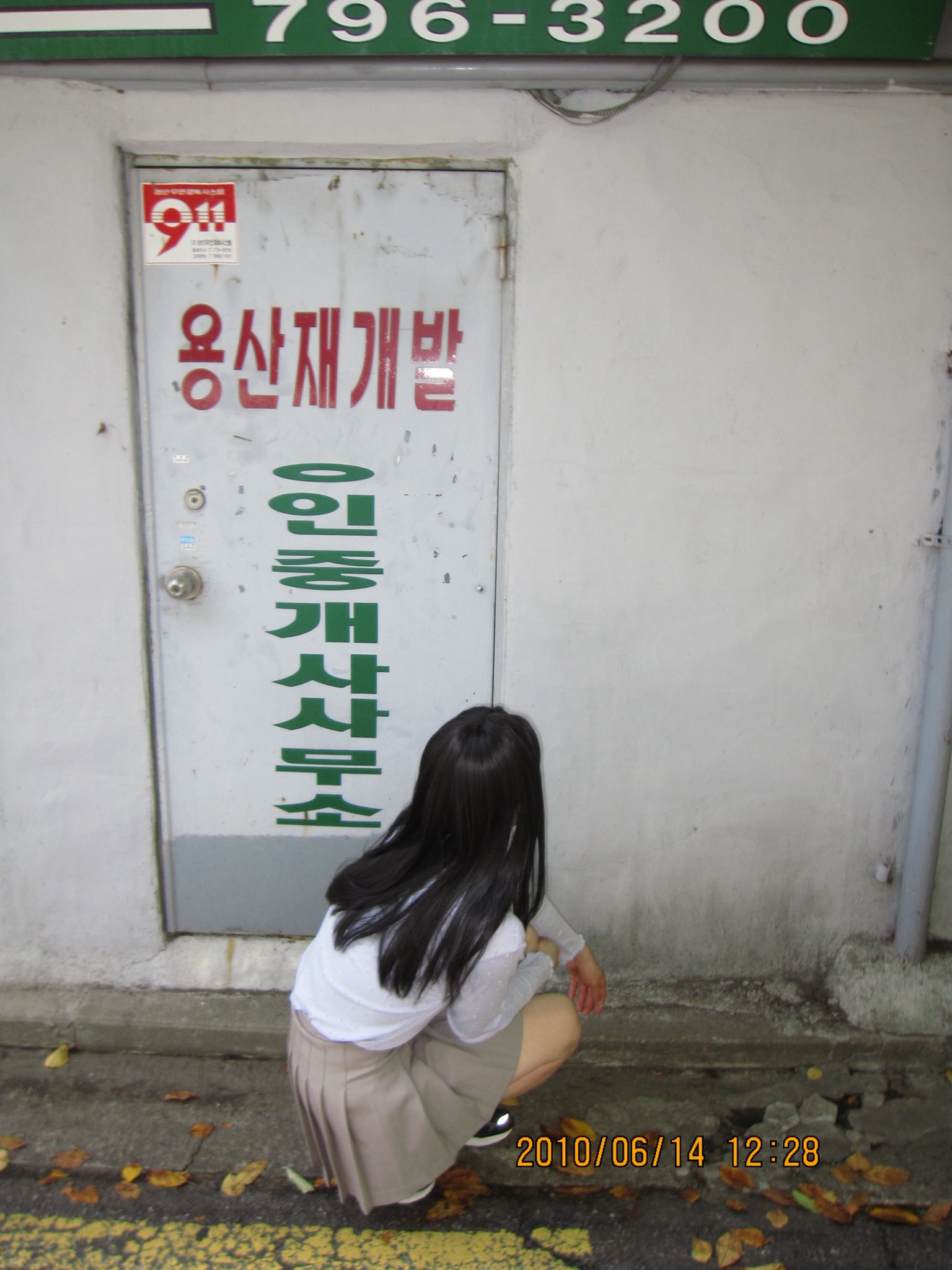 一位穿着裙子的女人挂着一幅画在墙上。