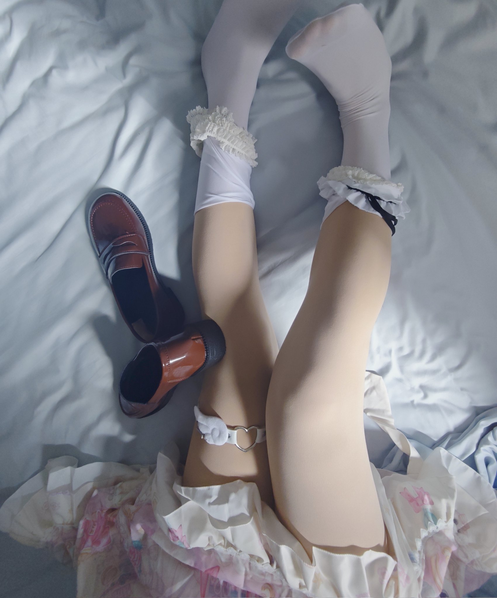 一位穿着裙子和袜子的女人躺在床上,旁边有一双鞋子。