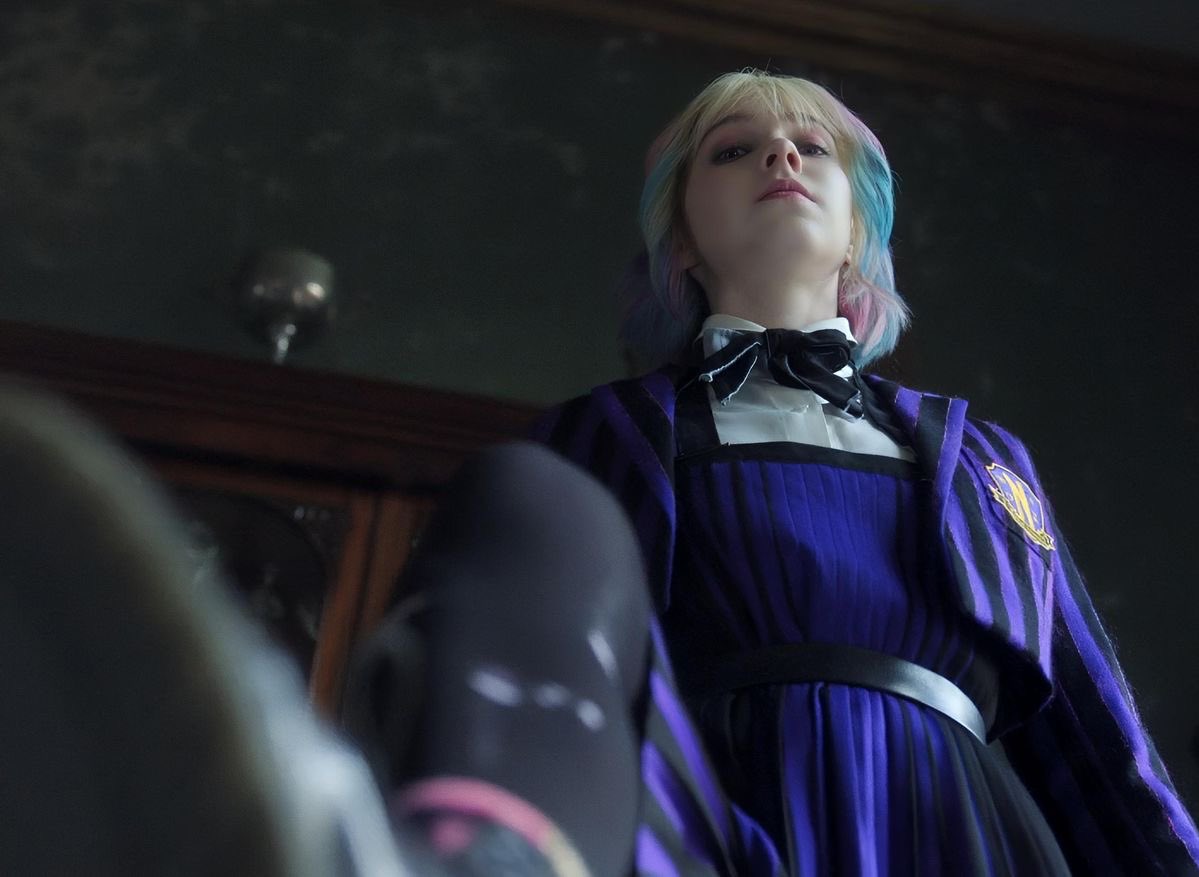 带着蓝色弓带和紫色头发的女孩站在一个戴着粉红袜子的男人身上。